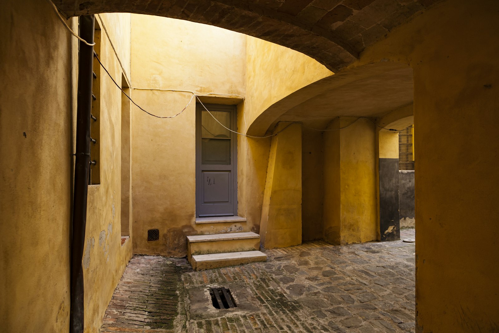 A quiet vaulted stone lane in Siena's medieval center, worn smooth underfoot. Photo by Paolo D'Andrea on Unsplash.
