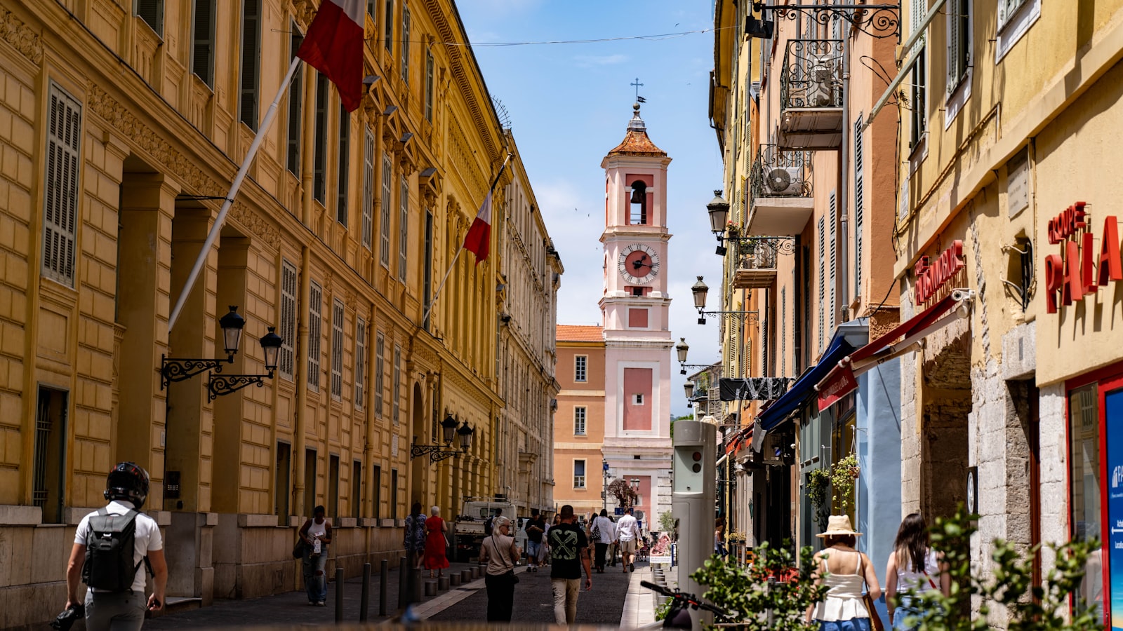 A busy Vieux Nice lane of shops and cafés below the pink bell tower, in the old town of Nice. Photo by Rich Martello on Unsplash.