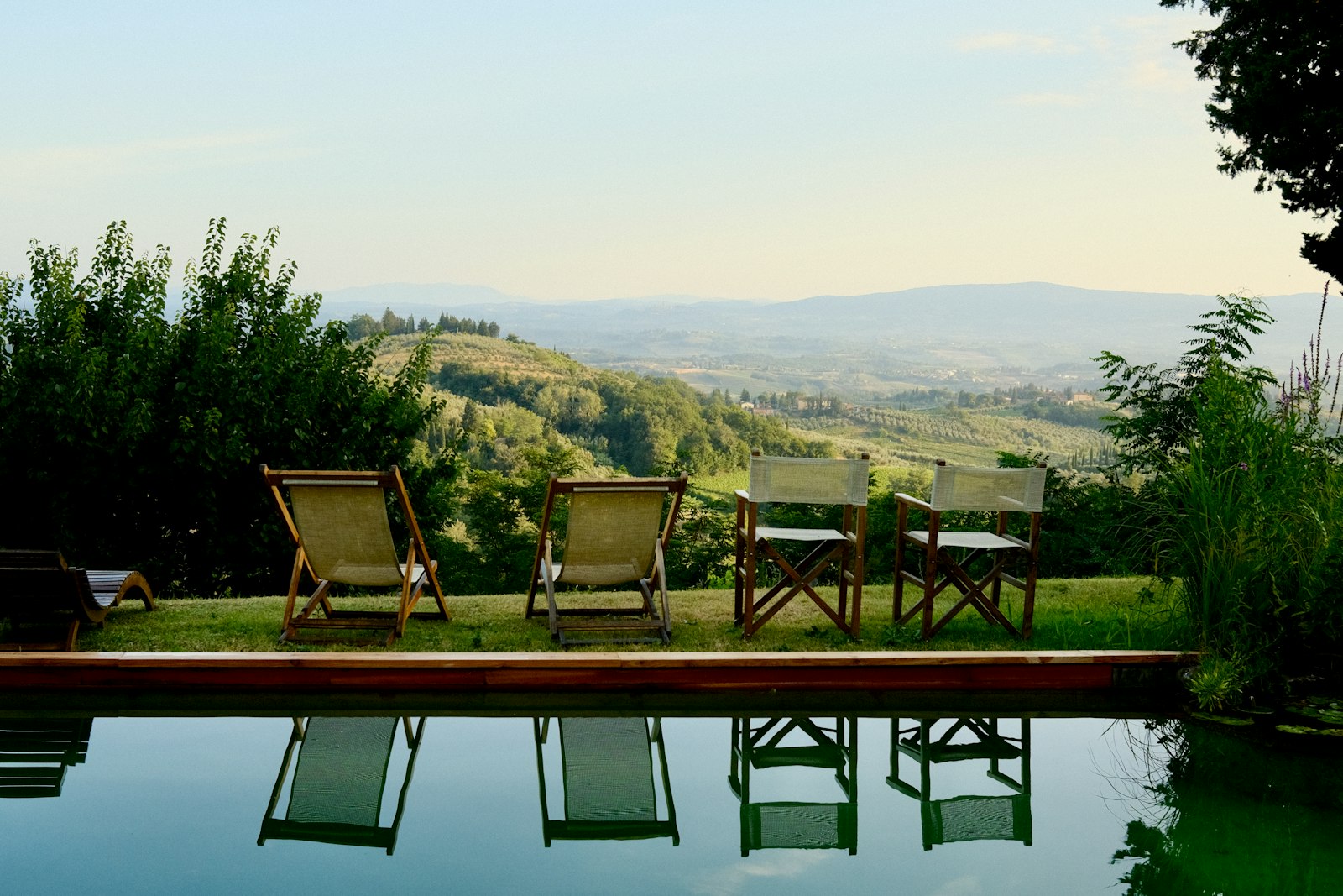 Tumbonas junto a una piscina con vista a las colinas de la Toscana. Foto de Ronan Laker en Unsplash.
