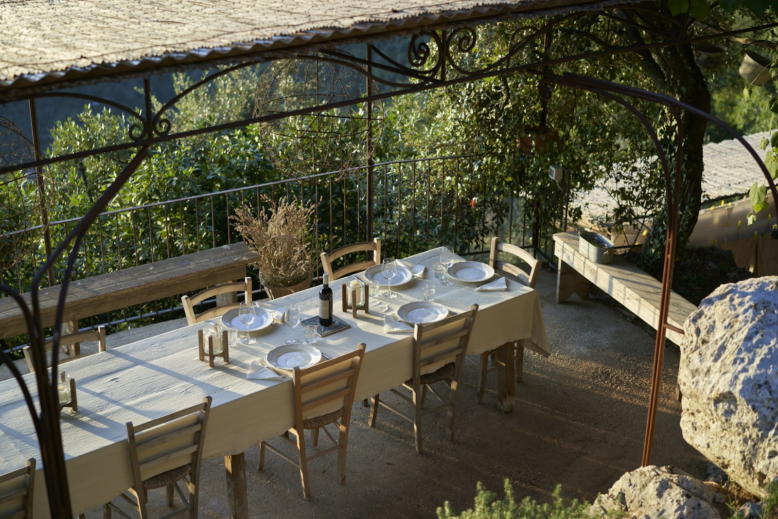 Una mesa larga puesta para una cena de grupo en una terraza de piedra bajo una pérgola en la Toscana. Foto de Steffen Lemmerzahl en Unsplash.