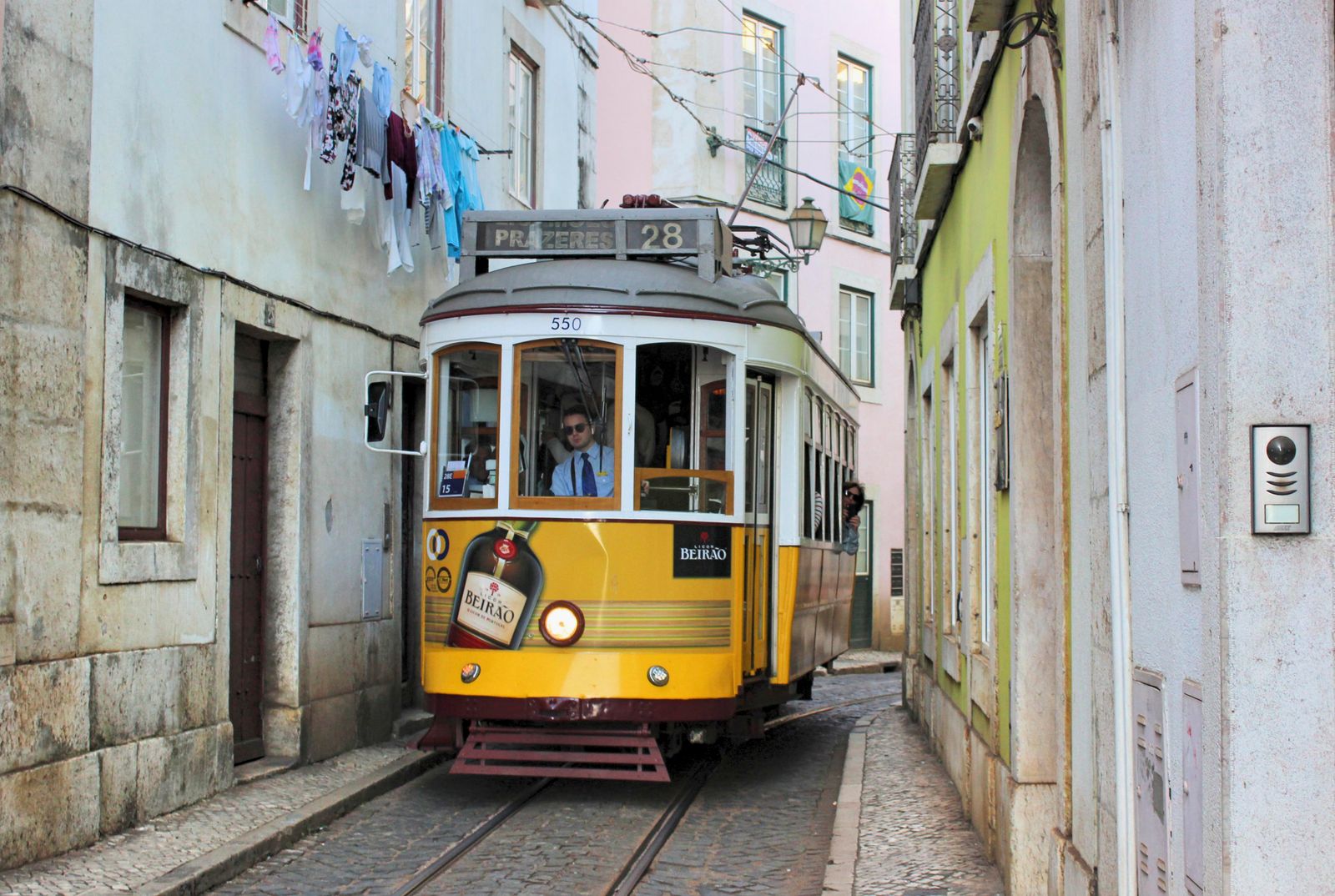 El tranvía 28 en una callecita angosta de Alfama, con tendederos sobre la calle. Foto de Miguel A. Ferreira en Pexels.