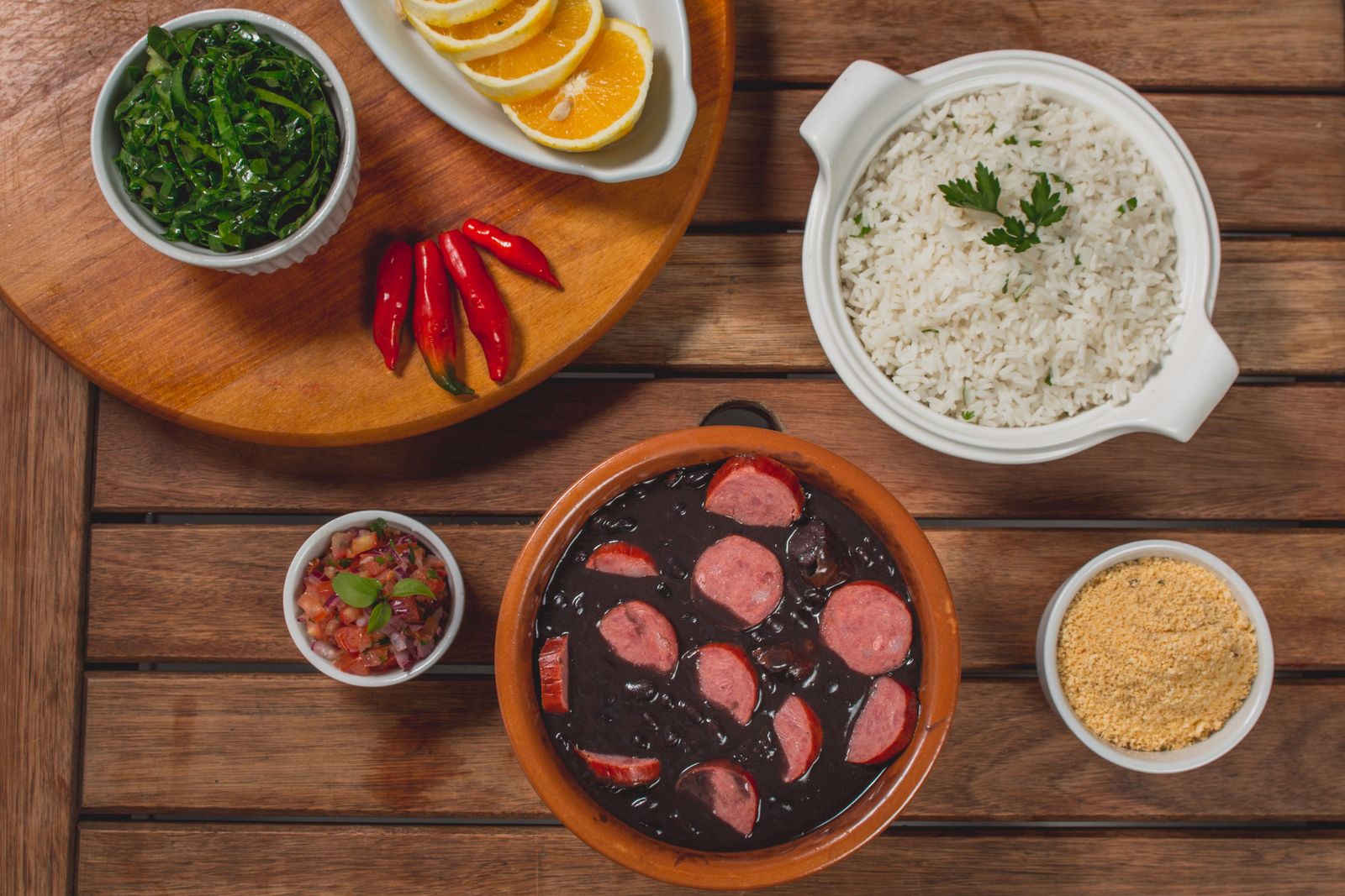 A pot of Brazilian black bean stew with rice, greens, farofa and orange. Photo by José Roberto Oliveira on Pexels.