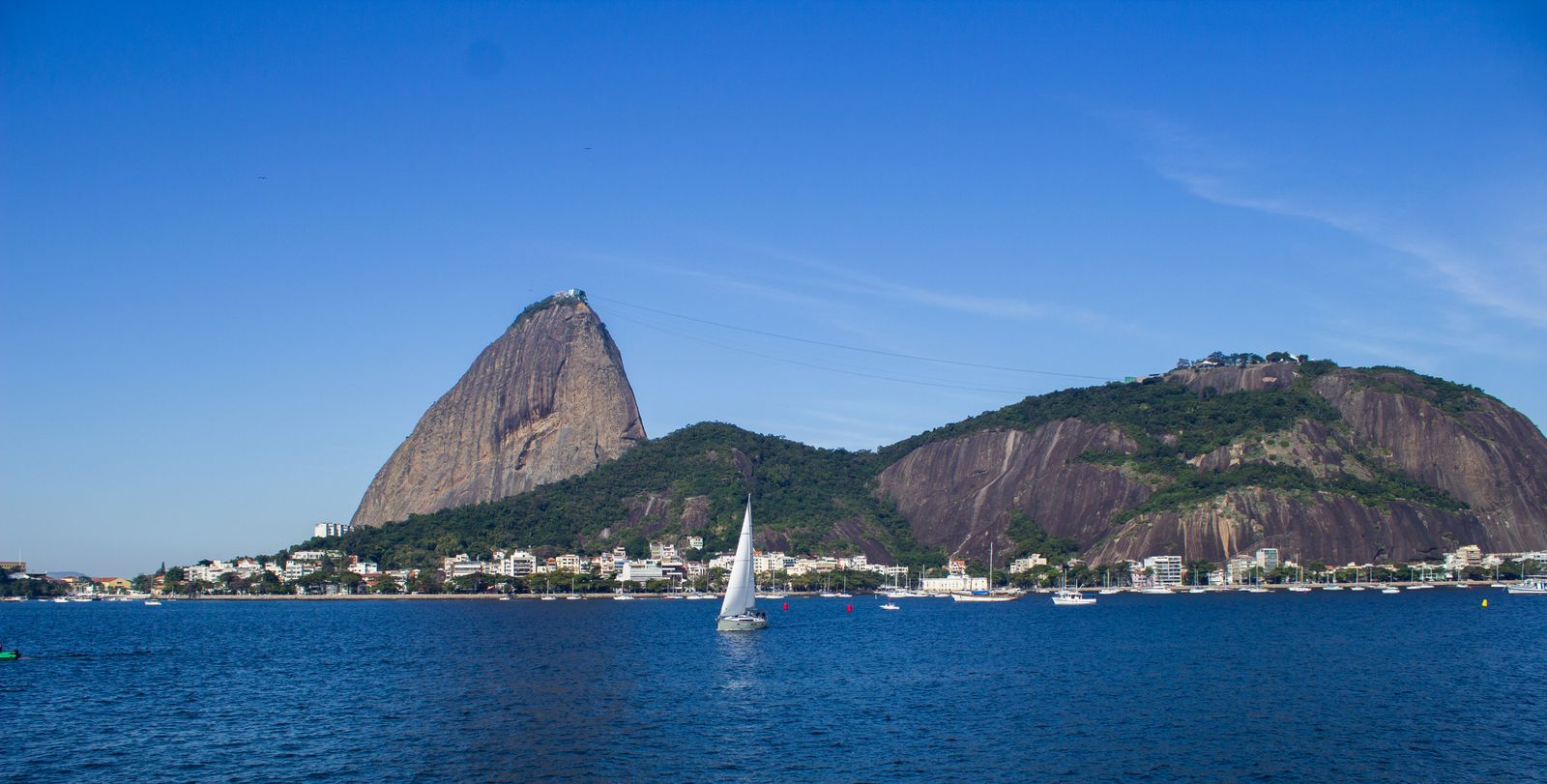 Sugarloaf Mountain across the water from Botafogo, with a sailboat in the bay. Photo by Arnaldo Silva on Pexels.