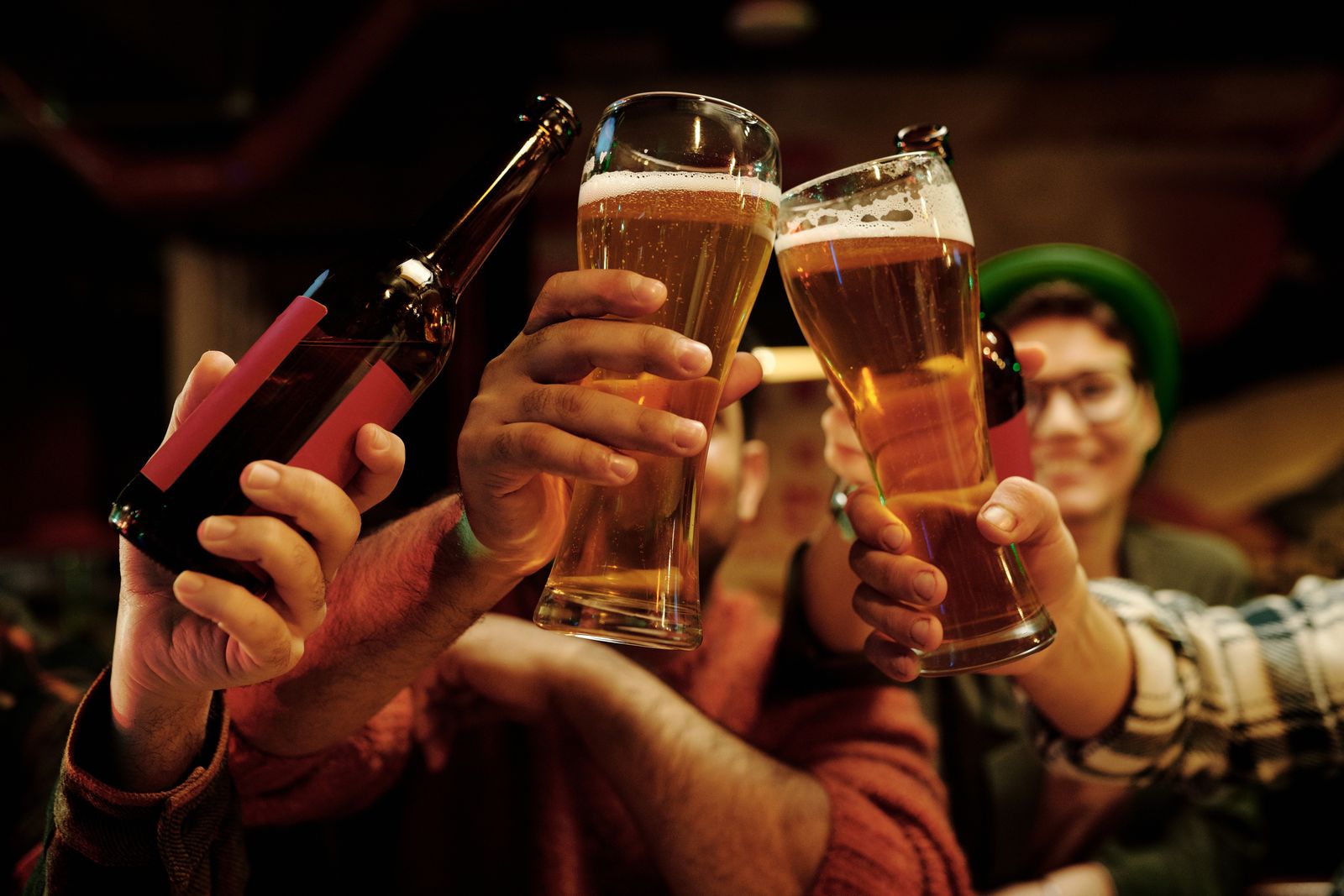Friends raising glasses of beer together in a bar. Photo by Darlene Alderson on Pexels.