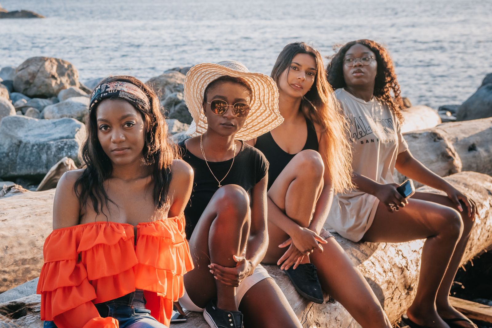 Four friends sitting together on the rocks above the water. Photo by PNW Production on Pexels.