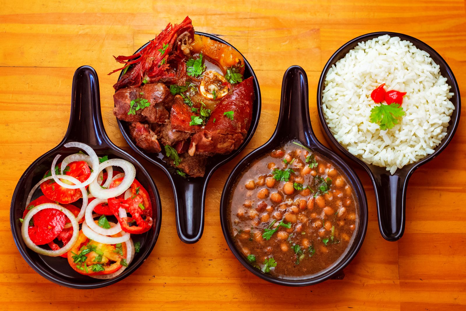Small pans of stewed beans, rice and grilled meat set out to share. Photo by Lucas Andrade on Pexels.