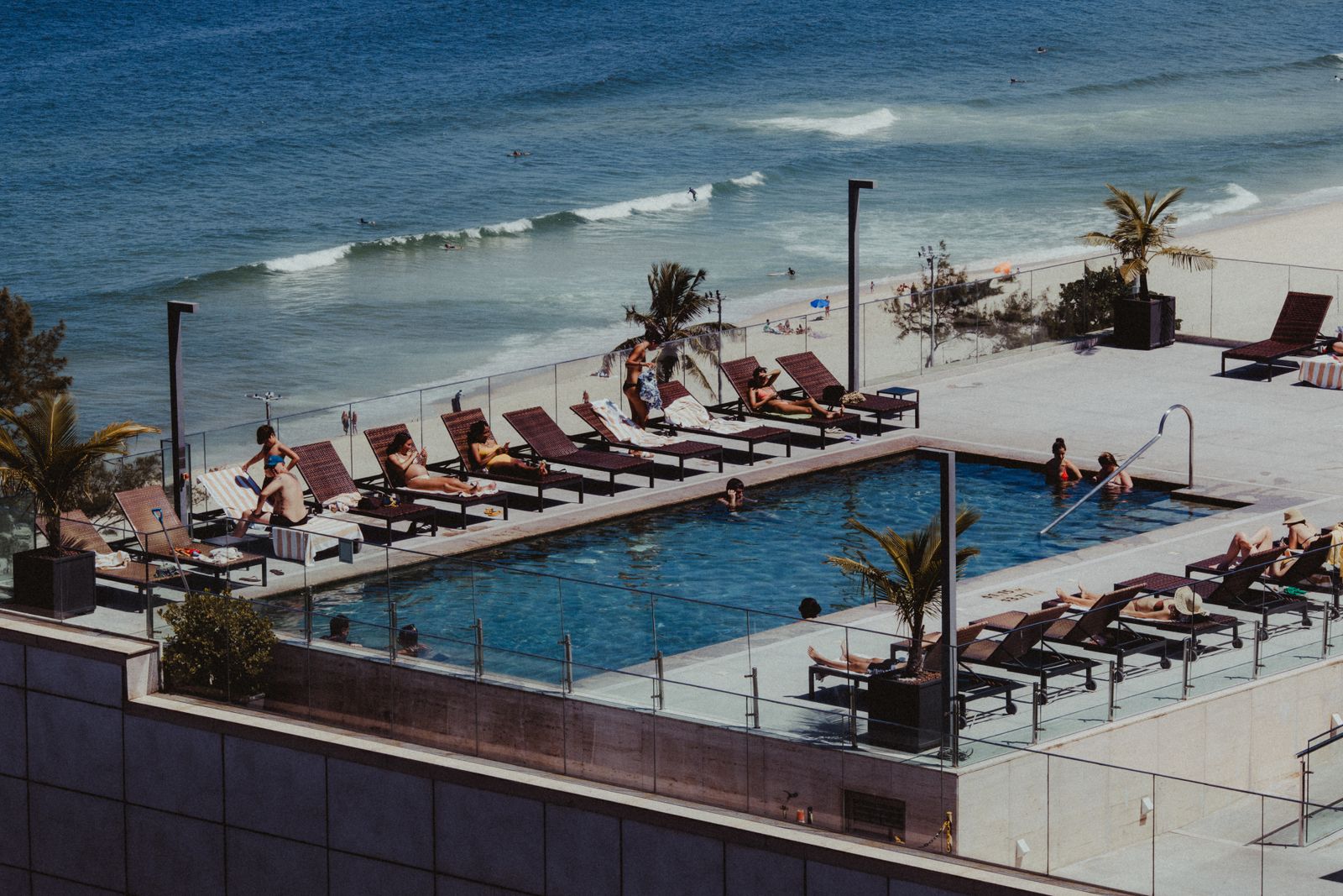 A rooftop pool and loungers looking out over the surf. Photo by Jonathan Borba on Pexels.