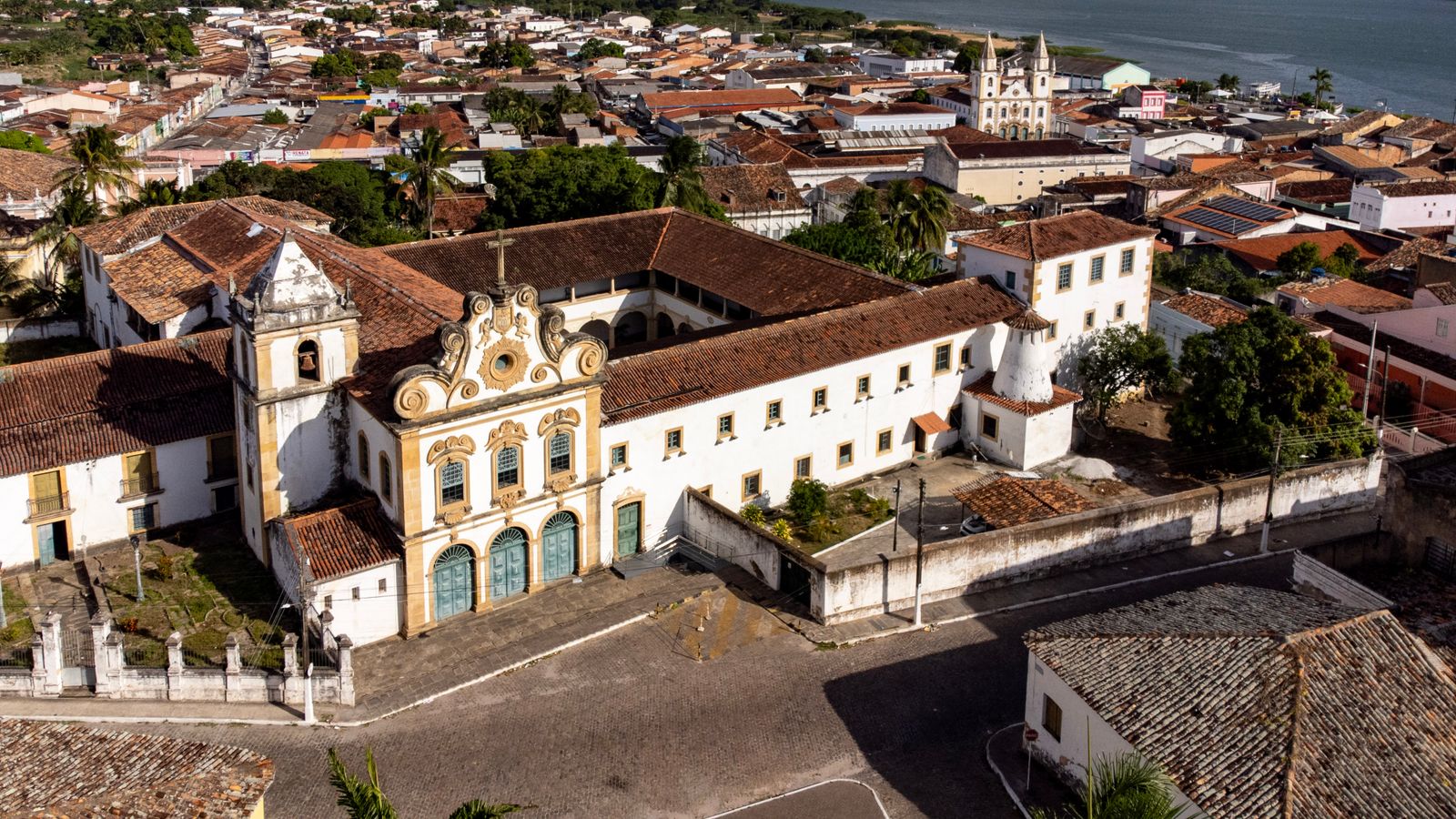 An aerial view of an old Brazilian colonial town, its church and tiled roofs above the water. Photo by Bruno Vieira on Pexels.