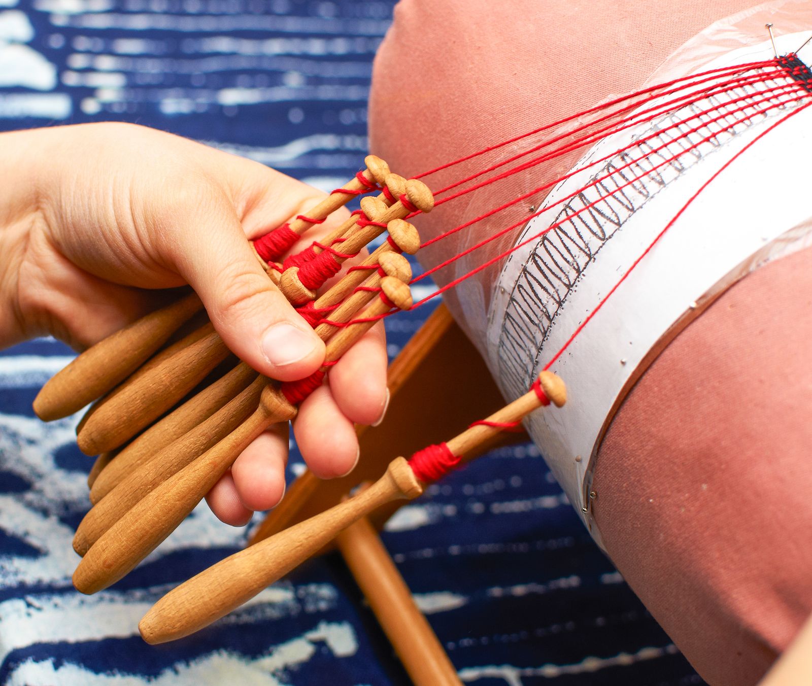 Las manos de una encajera moviendo bolillos de madera sobre una almohadilla de encaje. Foto de Vladimír Sládek en Pexels.