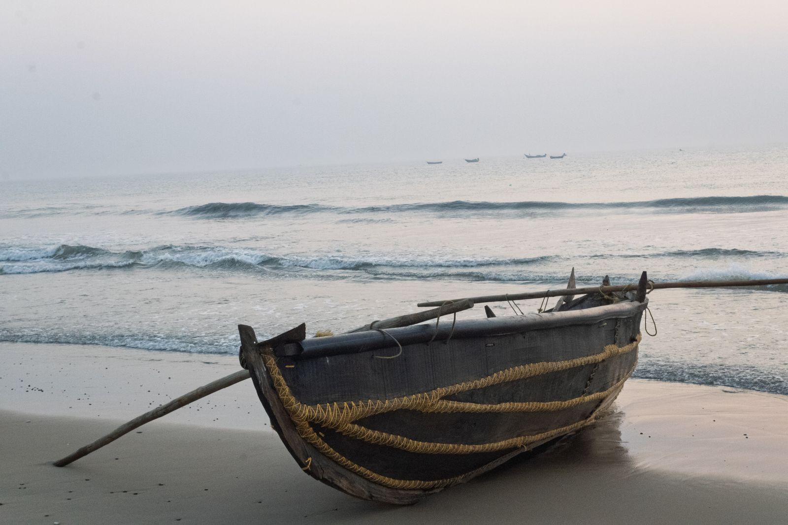 Una canoa de pesca de madera varada en la arena al final del día. Foto de Jayesh Krishna Althi en Pexels.