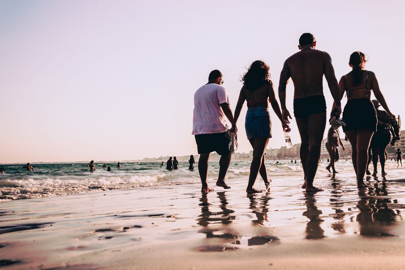 A group of friends walking together along the wet sand of a sunlit beach. Photo by Victor Freitas on Pexels.