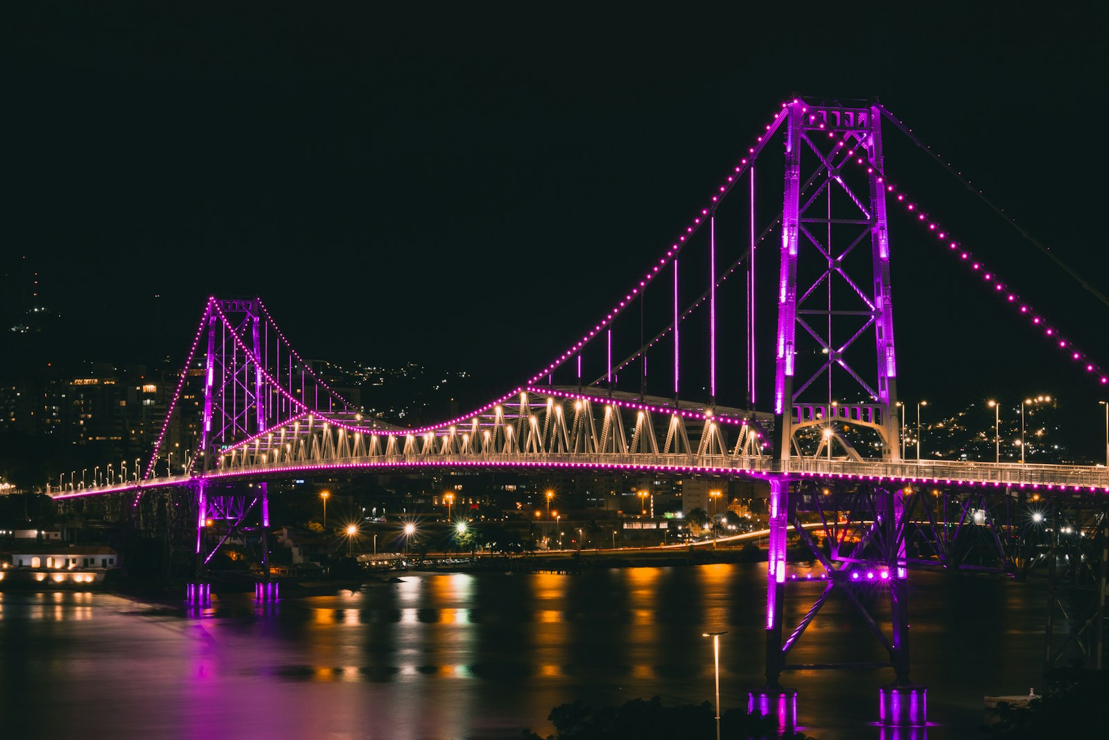 La Ponte Hercílio Luz iluminada de noche sobre la bahía de Florianópolis. Foto de Tiago Muraro en Unsplash.
