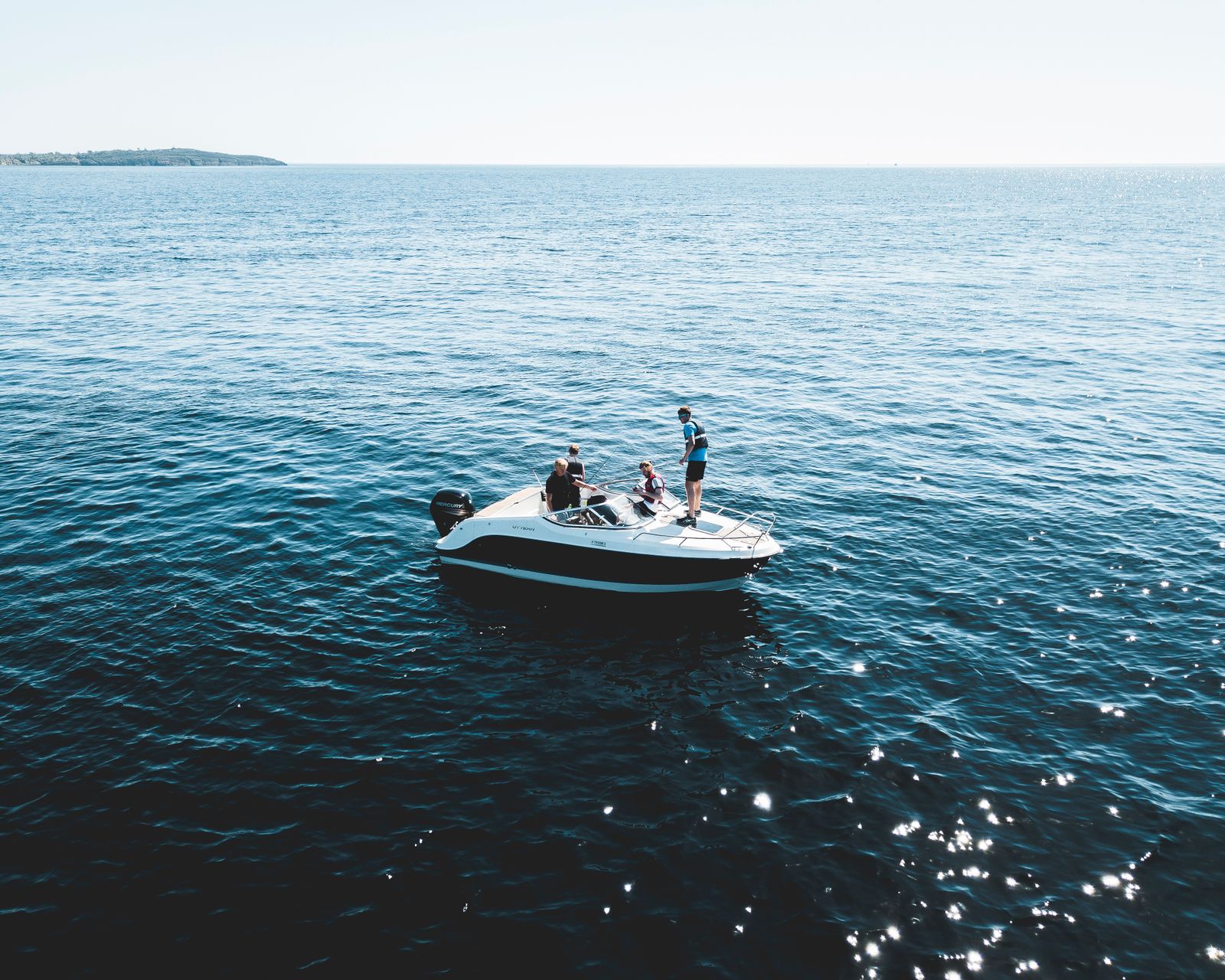 A small motorboat with people aboard on open blue water. Photo by Sindre Fs on Pexels.