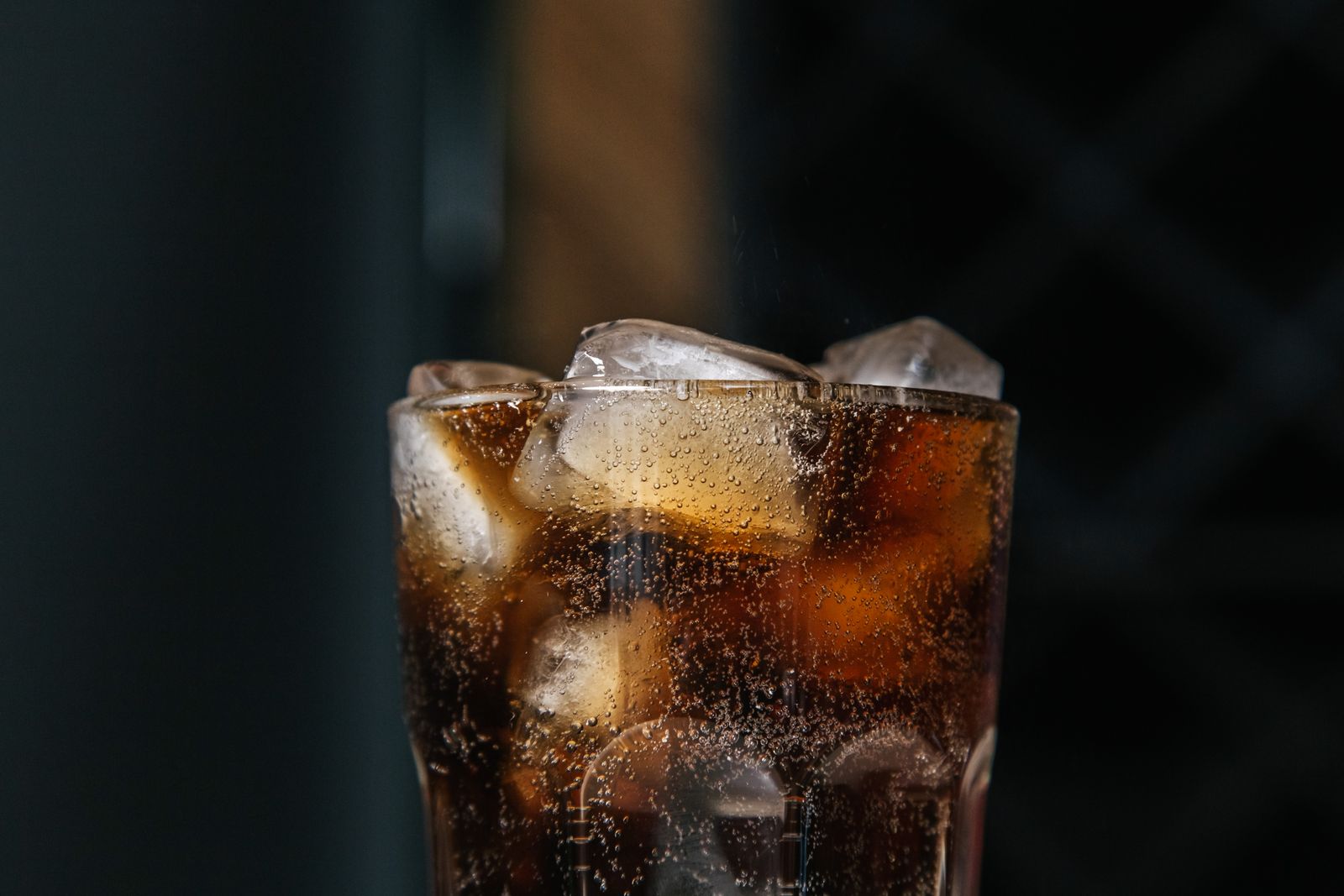 Un vaso alto con una bebida oscura servida sobre hielo. Foto de Ron Lach en Pexels.