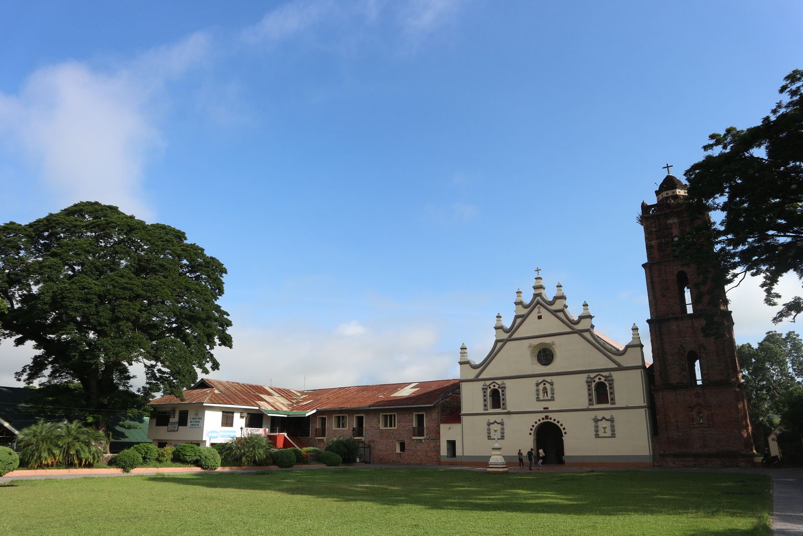 A white colonial church and its low outbuildings across a lawn. Photo by Elmer Domingo on Pexels.
