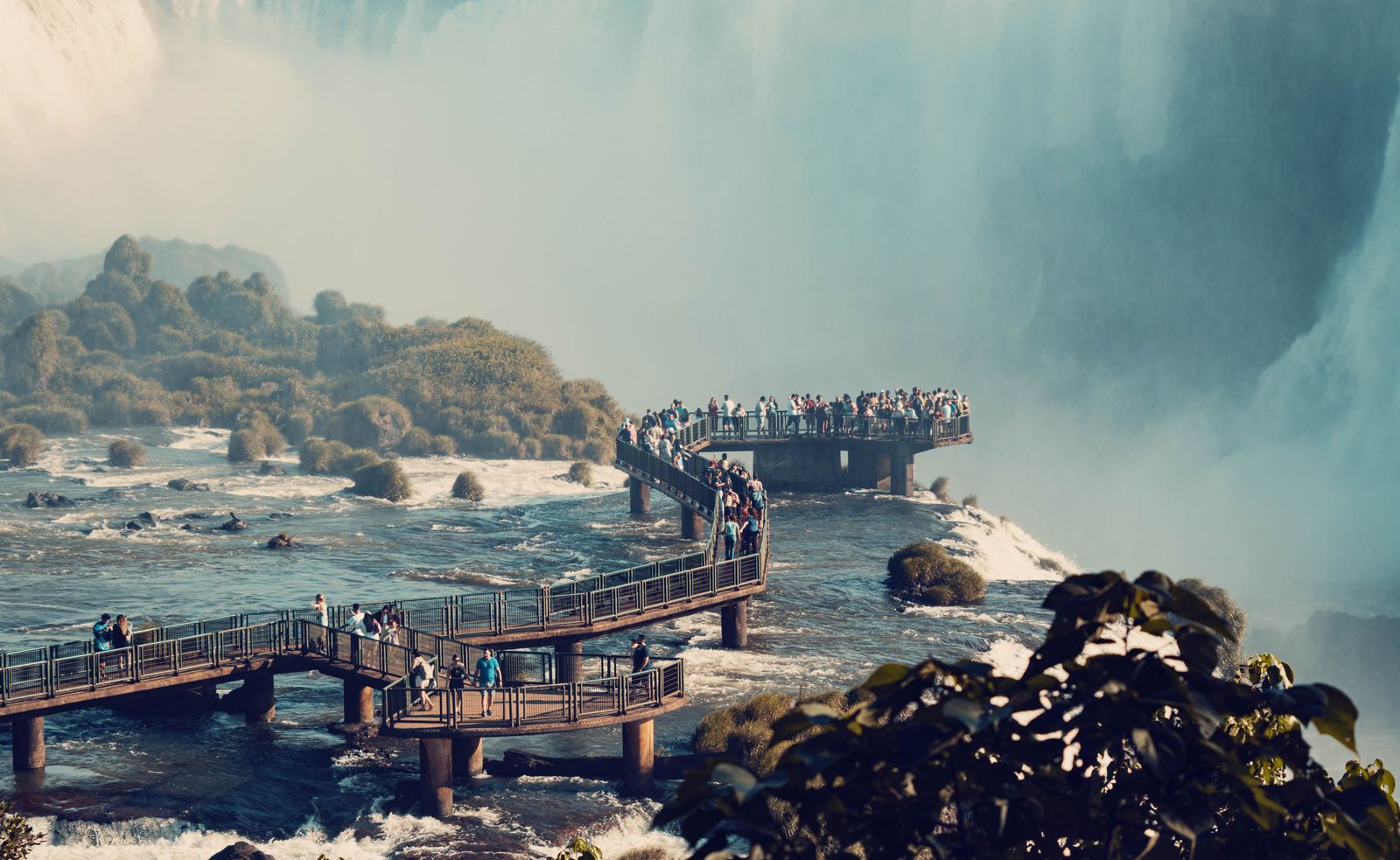 A walkway running out over the water toward the falls. Photo by JAIRO BEIZA on Pexels.