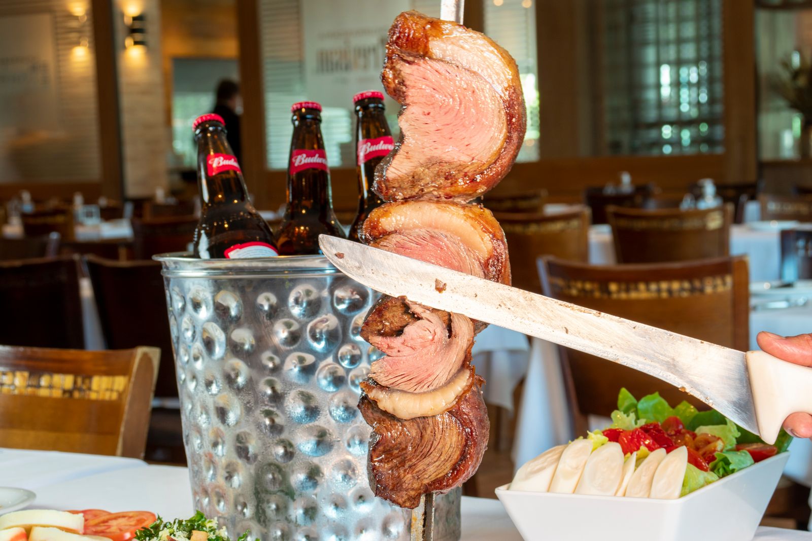 Picanha being carved off a skewer at the table at a Brazilian rodízio. Photo by Daniel Januario on Pexels.
