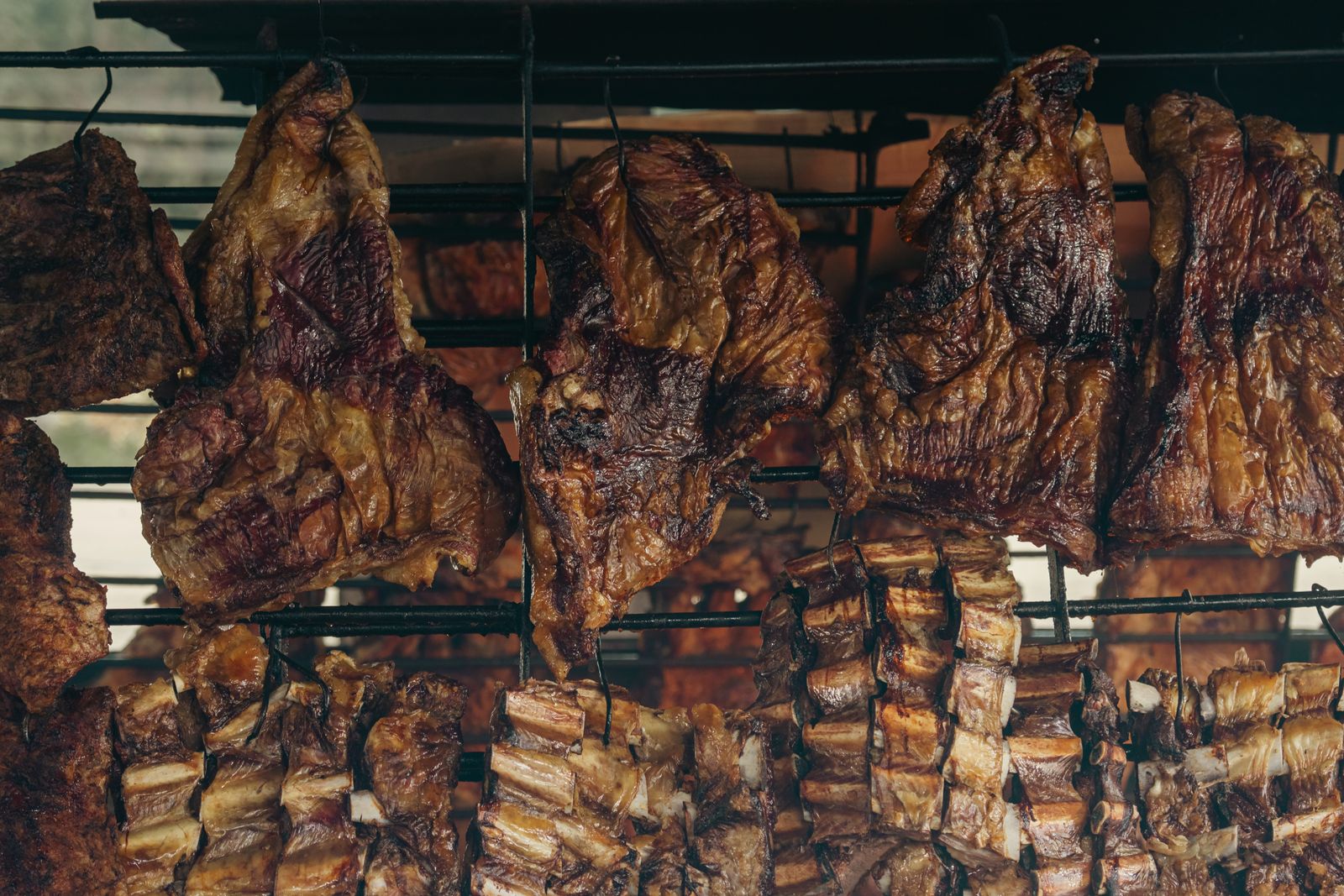 Racks of beef ribs hung over embers at an Argentine grill. Photo by Eduard Perez on Pexels.