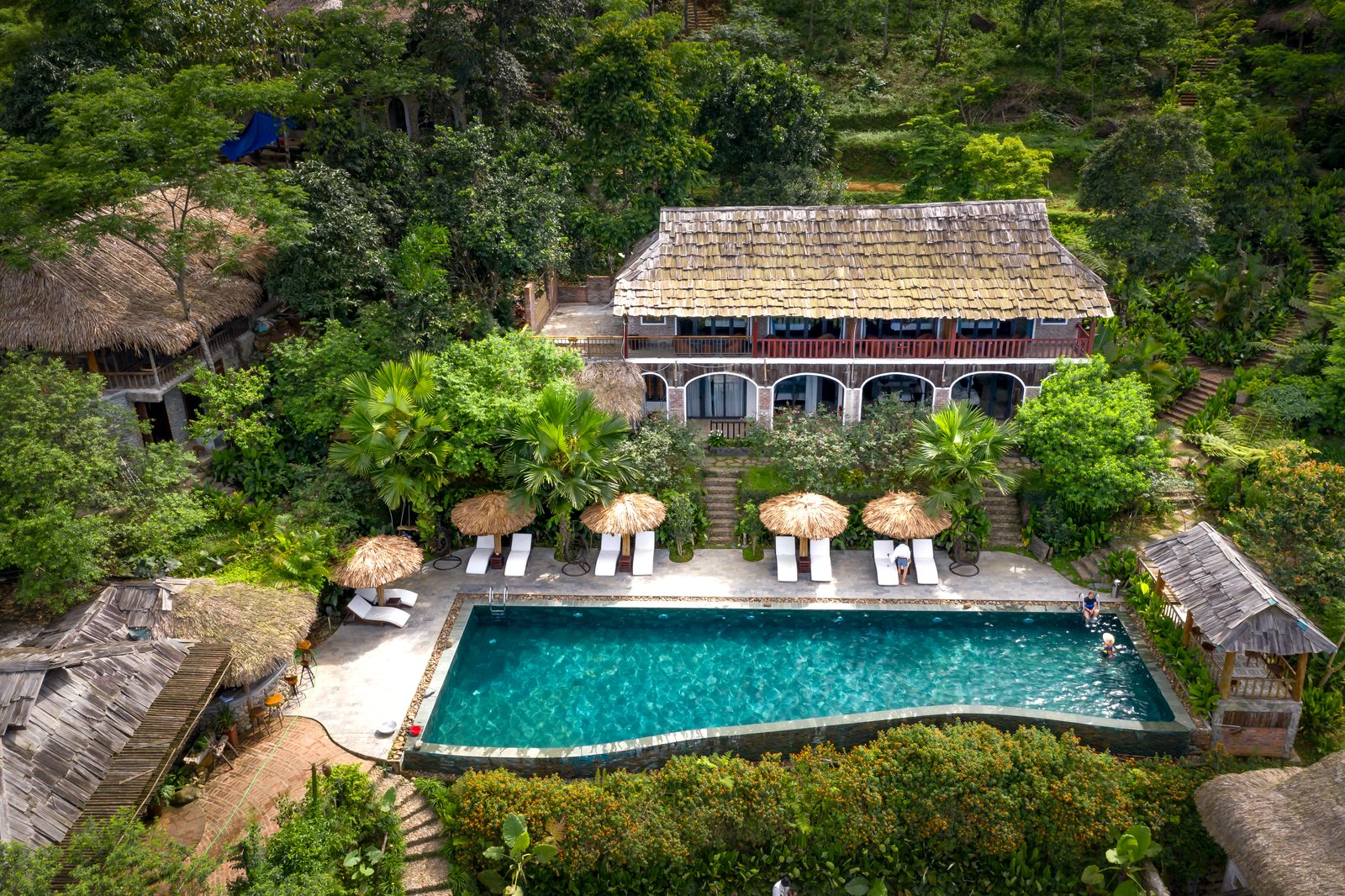 A large house with a long pool surrounded by dense green. Photo by Quang Nguyen Vinh on Pexels.