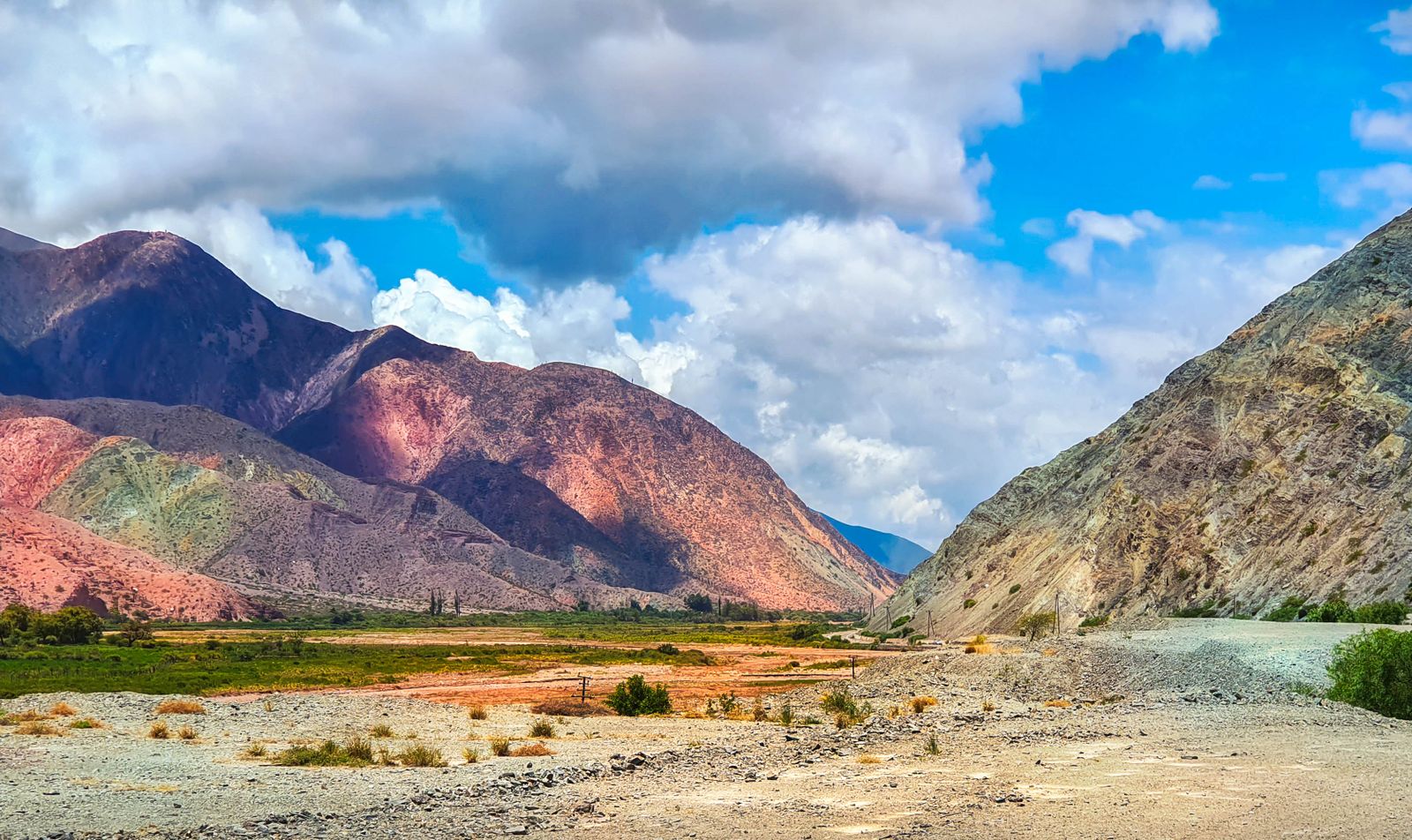 Franjas de roca roja, violeta y verde sobre el fondo de un valle en el noroeste argentino. Foto de Hector Perez en Pexels.