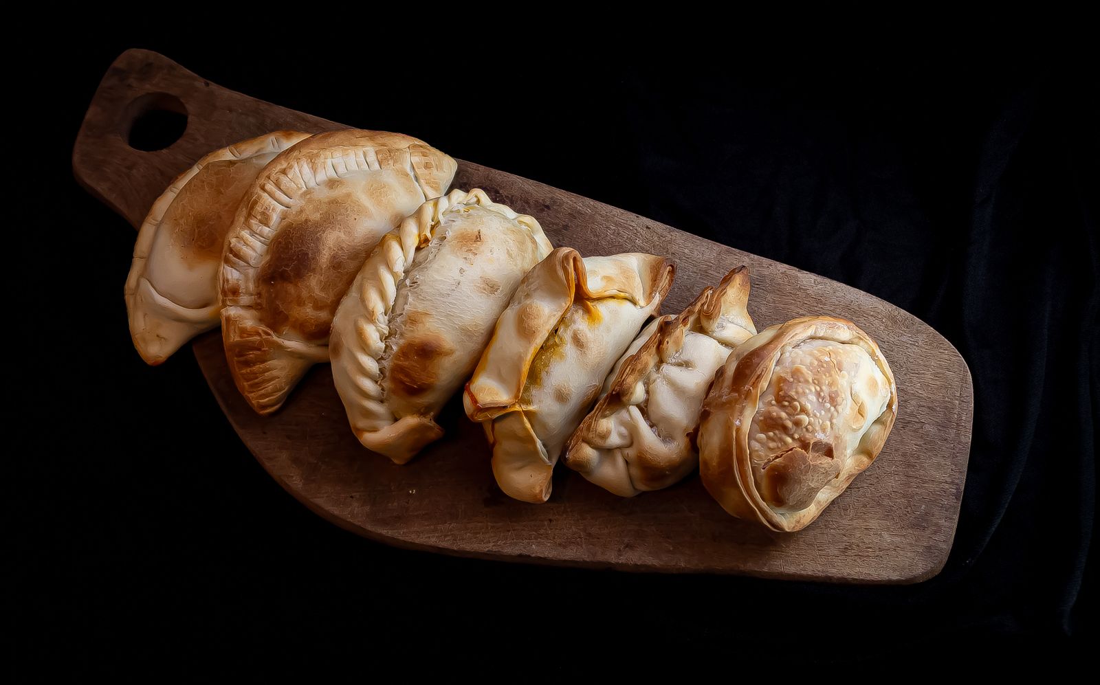 Una hilera de empanadas al horno sobre una tabla de madera. Foto de jessica olivella en Pexels.