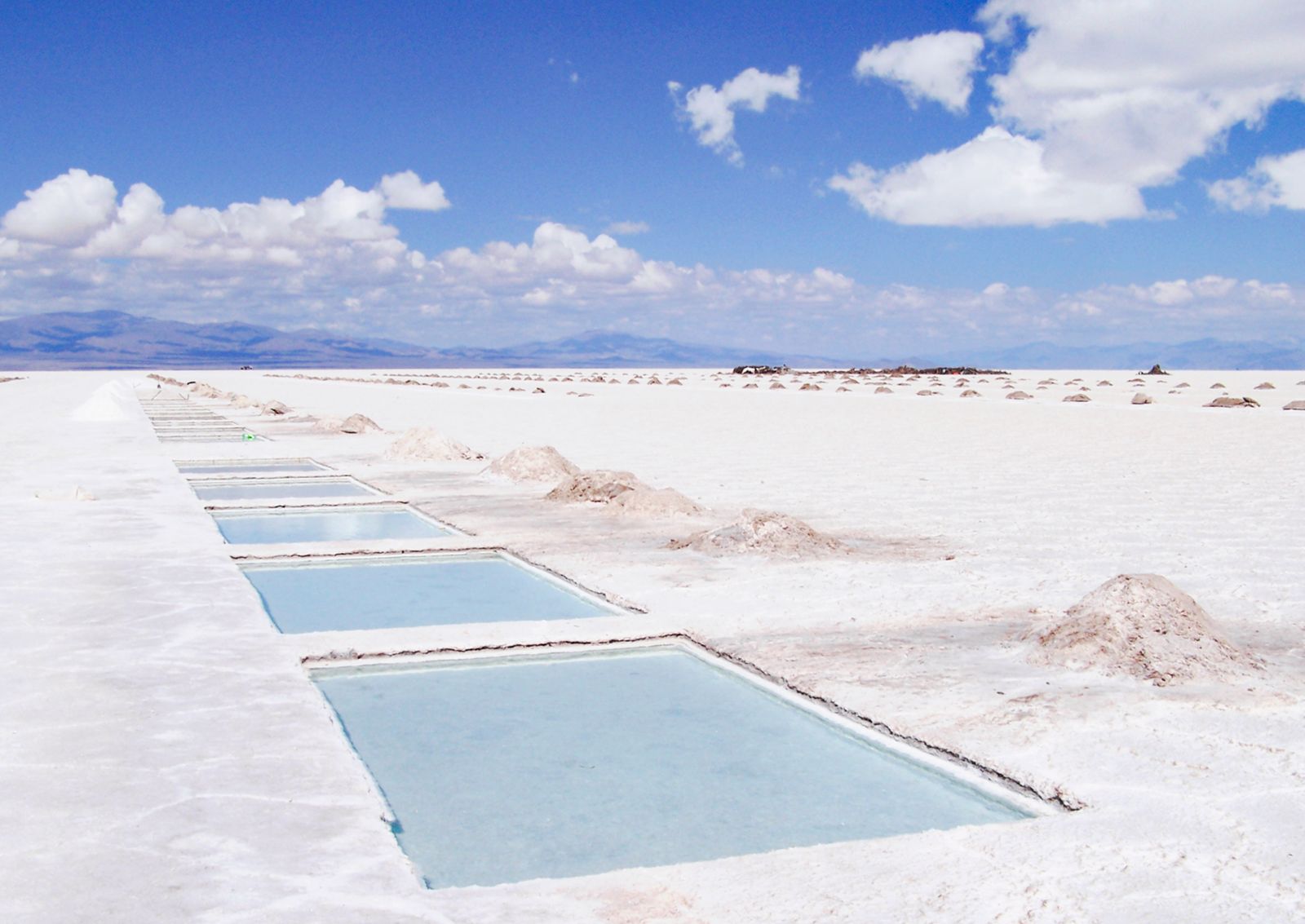 Rectangular pools of turquoise water cut into a white salt crust. Photo by Tom D'Arby on Pexels.