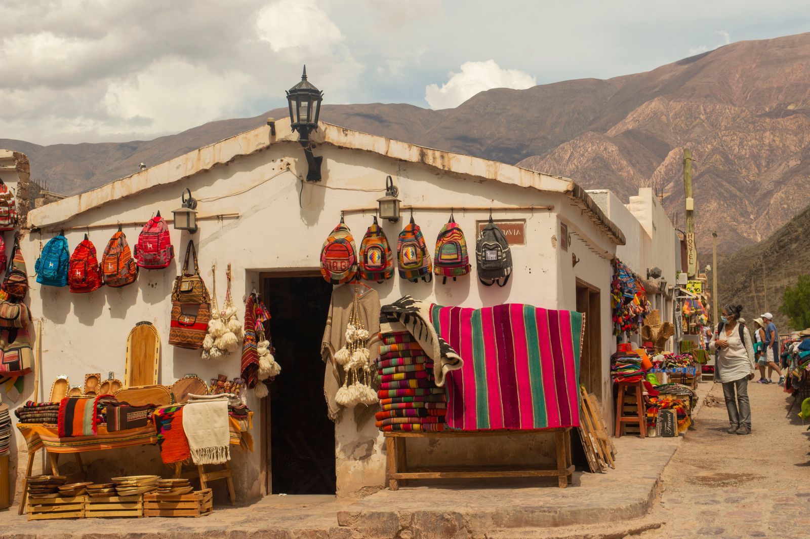 El frente de un local de artesanías con tejidos y bolsos colgados en un pueblo andino. Foto de Aldys Cattania en Pexels.