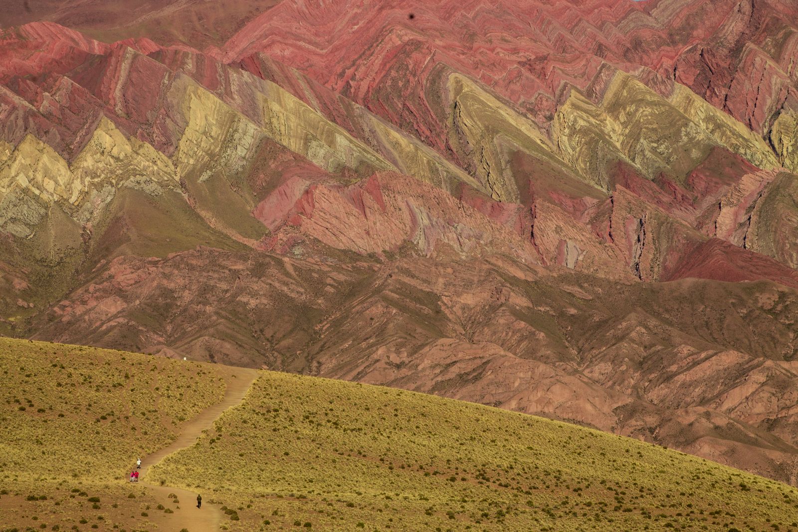 A mountainside of sharply folded rock in bands of red, yellow and green. Photo by Uriel Grillo on Pexels.