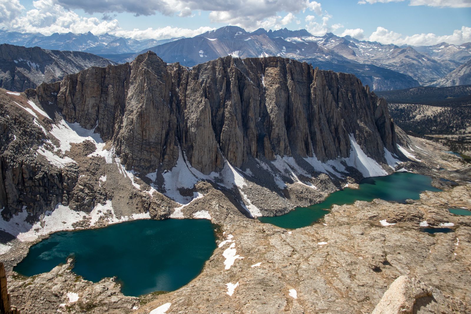 A small alpine lake held in a bowl of bare granite below a rocky cirque. Photo by Caleb Jack on Pexels.