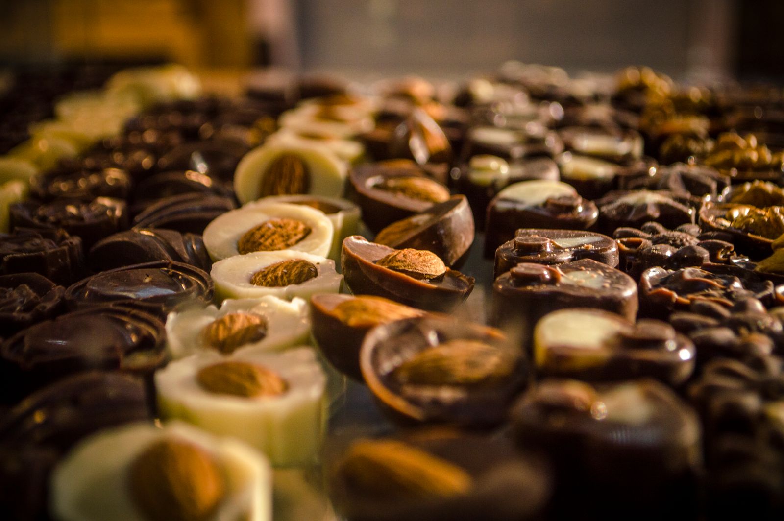 Trays of filled chocolates lined up on a counter. Photo by Francis Seura on Pexels.