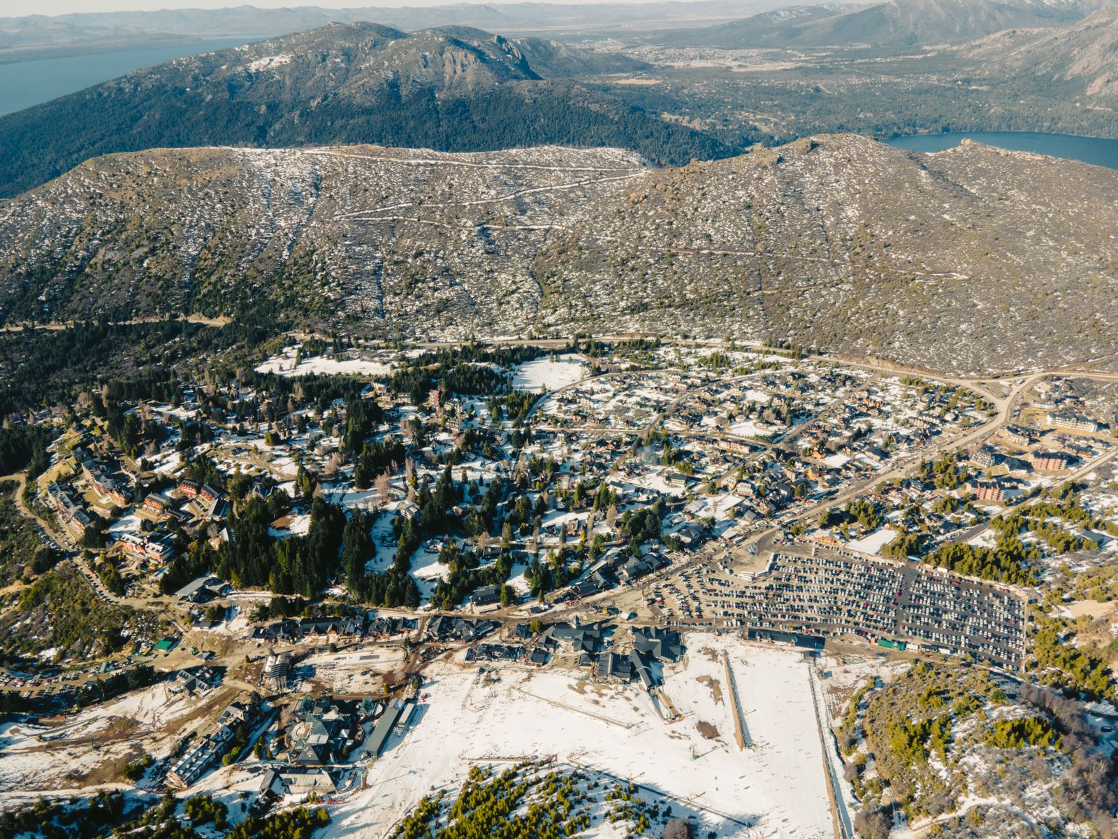 Bariloche seen from the air with snow lying over the town and the hills behind it. Photo by Pedro  Slinger on Pexels.