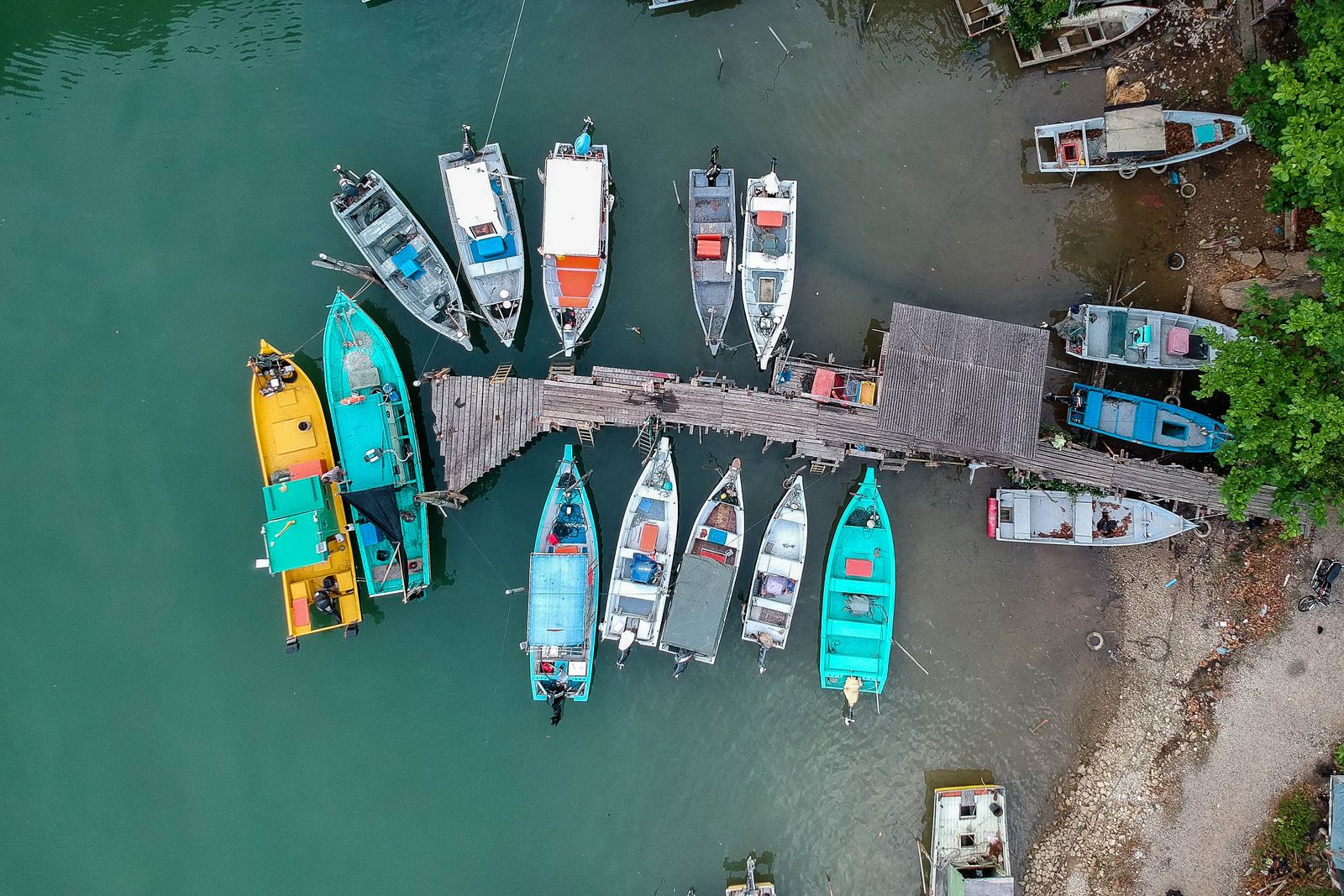 Small wooden boats tied up along a jetty, seen from above. Photo by Pok Rie on Pexels.