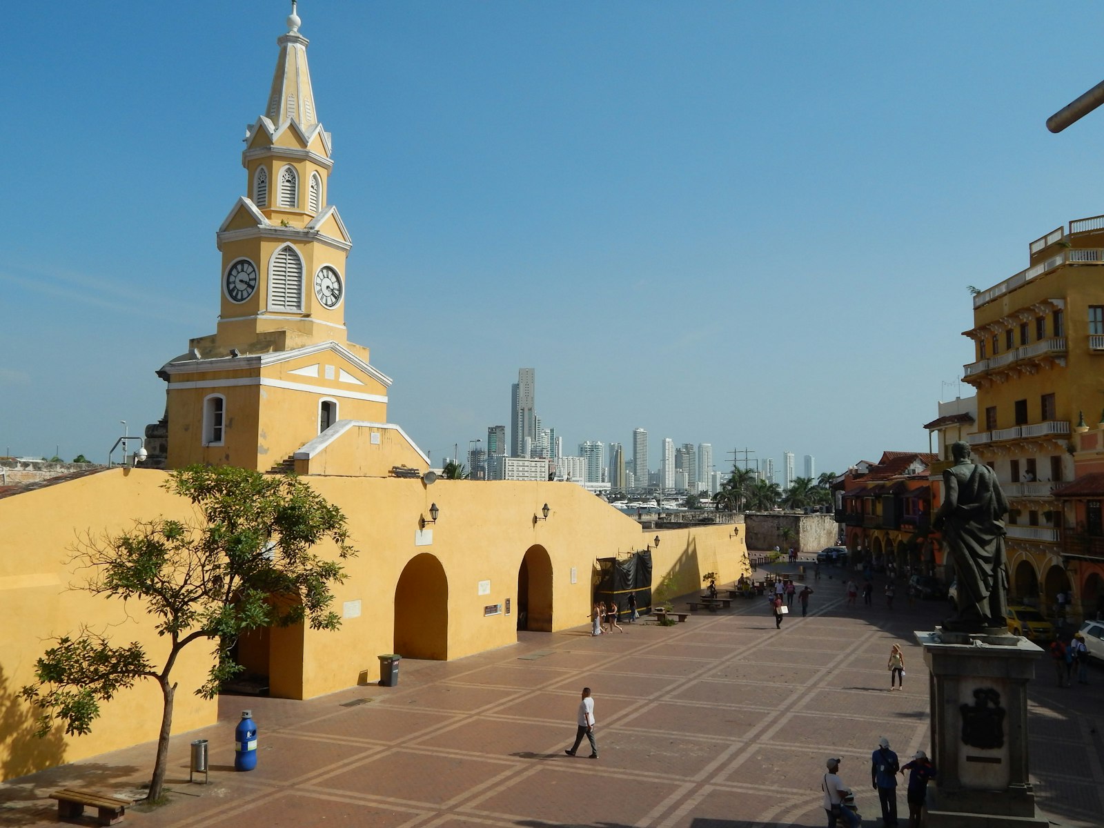 The yellow Torre del Reloj above the plaza at the entrance to Cartagena's walled city. Photo by Carlos Sarmiento on Unsplash.