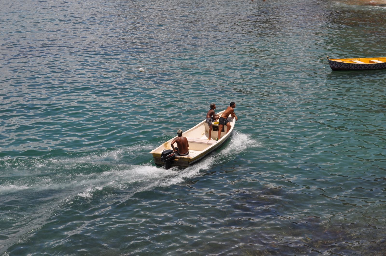 Three people in a small open boat with an outboard motor. Photo by Caio Arbulu on Pexels.