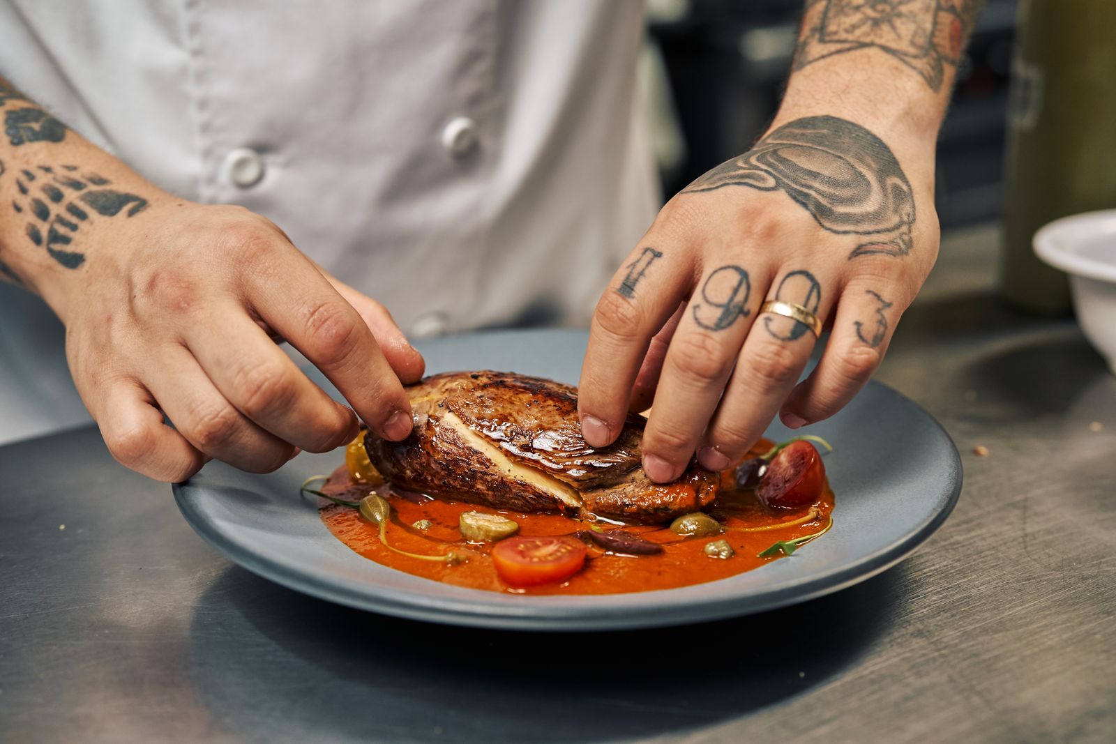 A cook finishing a plate in a restaurant kitchen. Photo by Willians Huerta on Pexels.