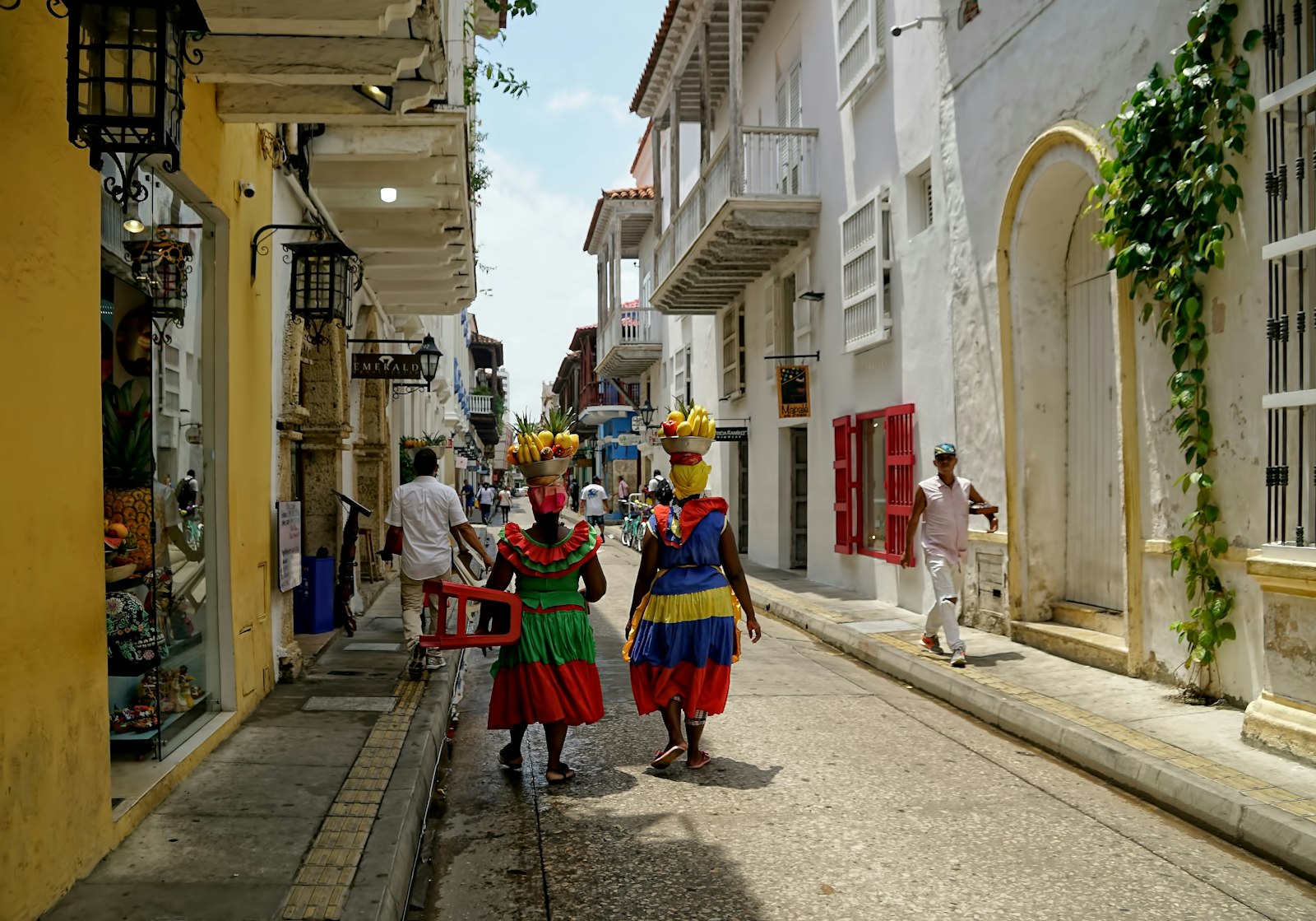 Two palenqueras walking a sunlit street in Cartagena's old city. Photo by Ricardo Gomez Angel on Unsplash.
