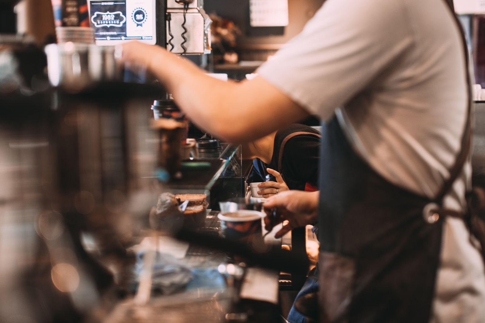 A barista making coffee at a busy walk-up counter. Photo by Rachel Claire on Pexels.