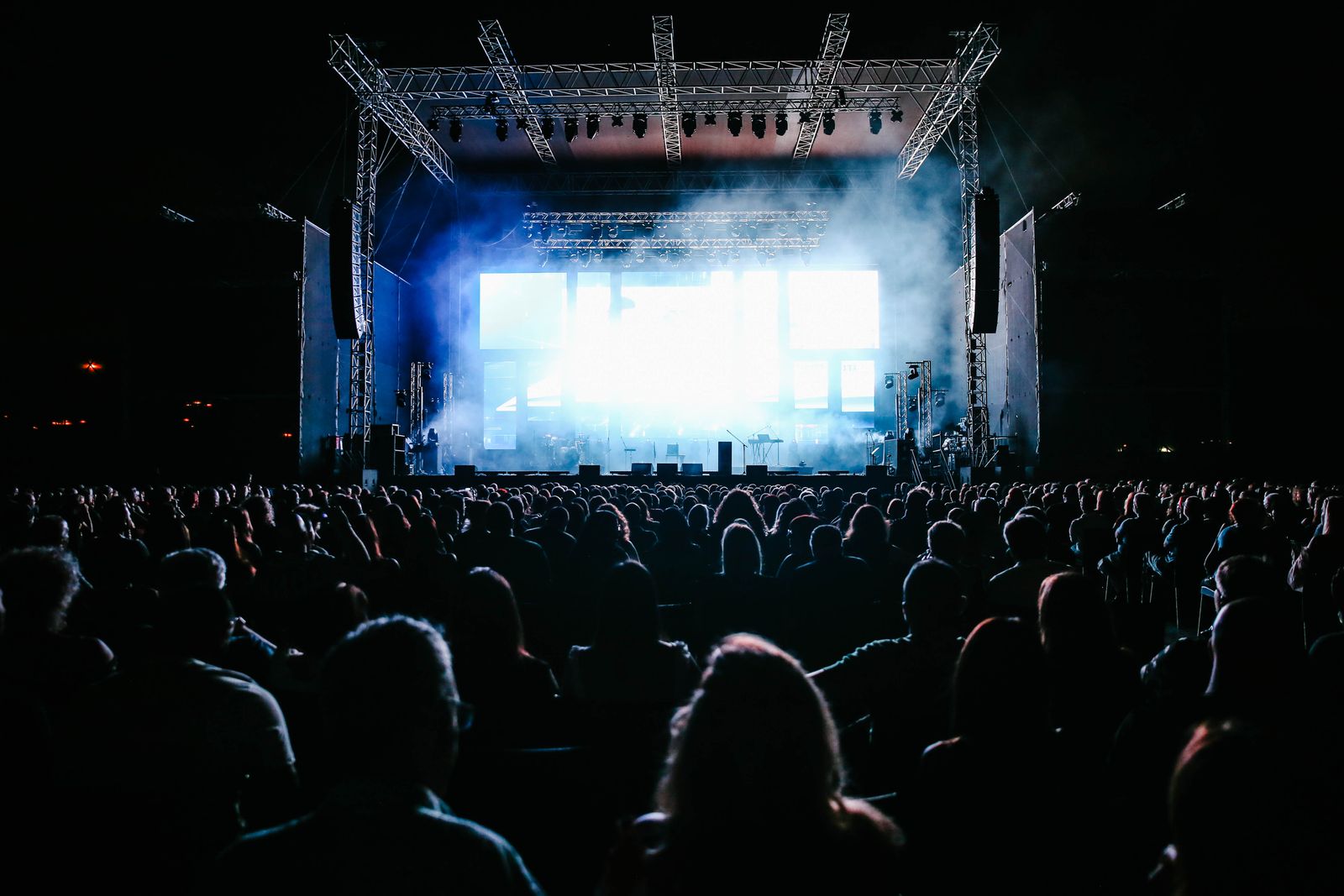 A crowd at an open-air concert in front of a lit stage at night. Photo by Maor Attias on Pexels.