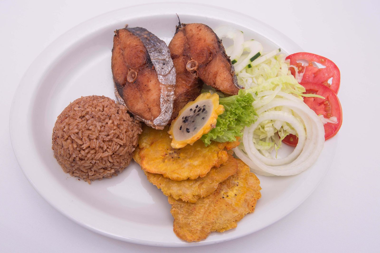 Fried fish with rice, plantains and salad on a plate. Photo by Jesus Cabrera on Pexels.