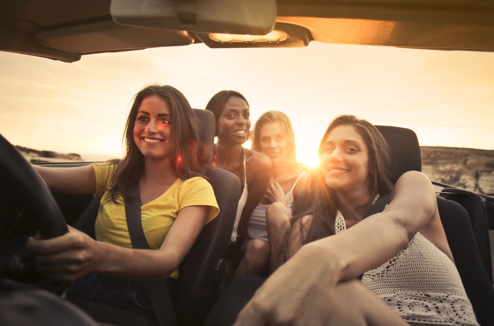 Four friends laughing together in a car at sunset. Photo by Andrea Piacquadio on Pexels.