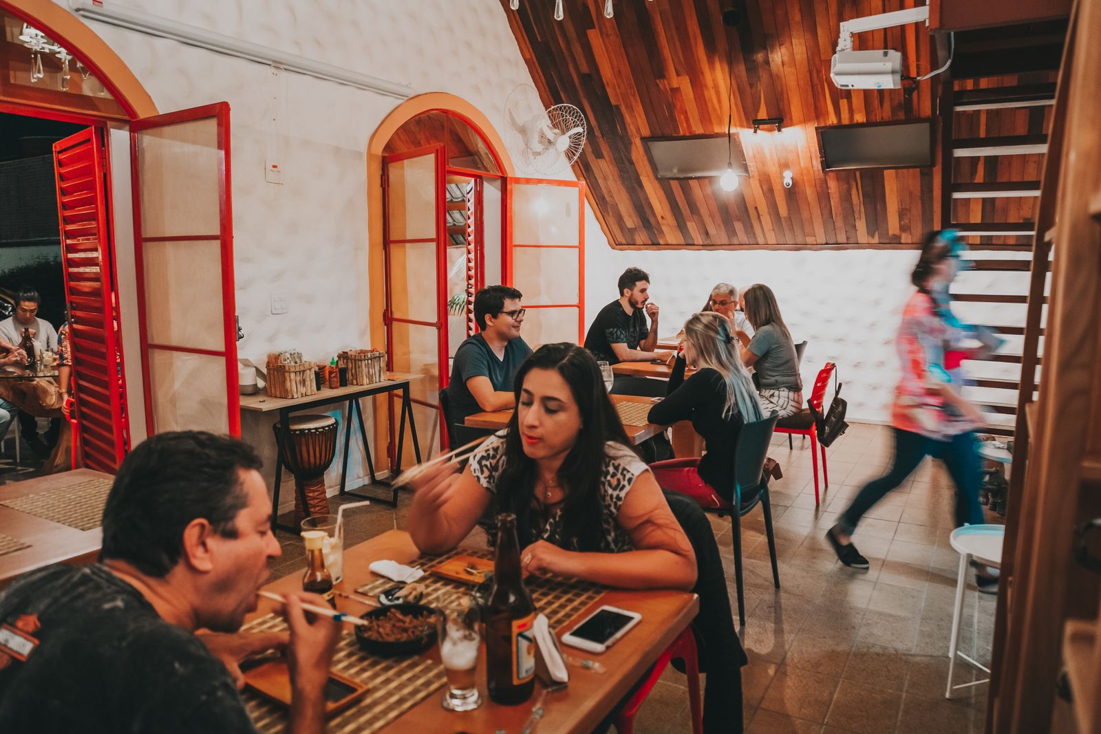 People eating and talking at wooden tables in a casual restaurant. Photo by Matheus Bertelli on Pexels.