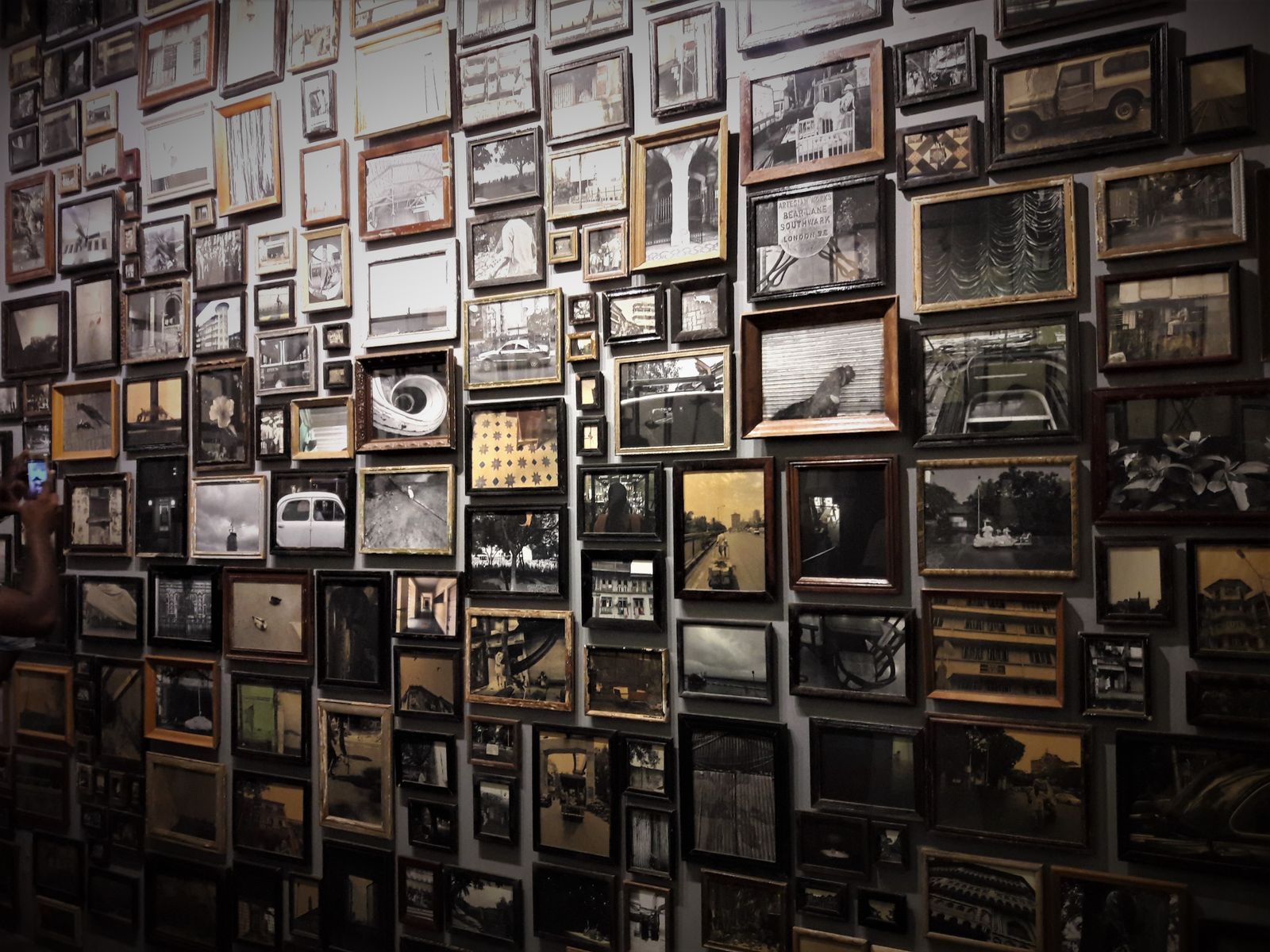 A wall densely hung with framed black-and-white photographs. Photo by Binil Babu on Pexels.