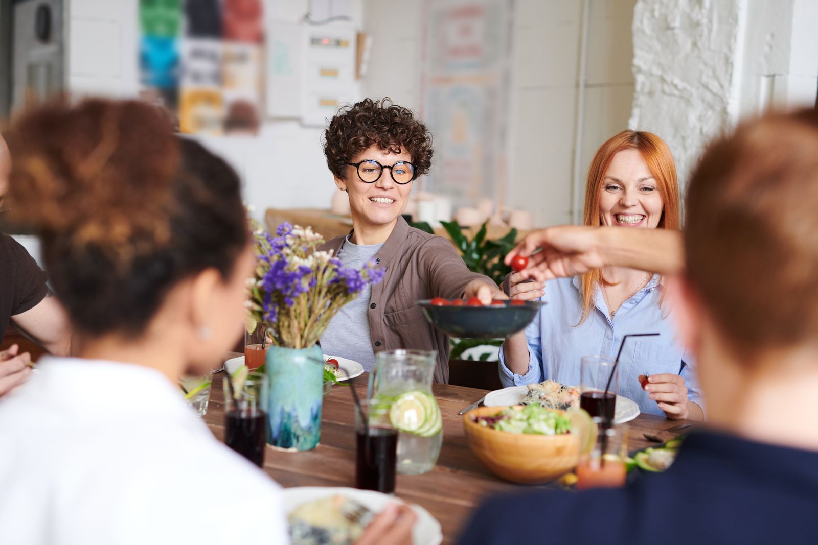 Friends passing dishes around a shared table indoors. Photo by fauxels on Pexels.