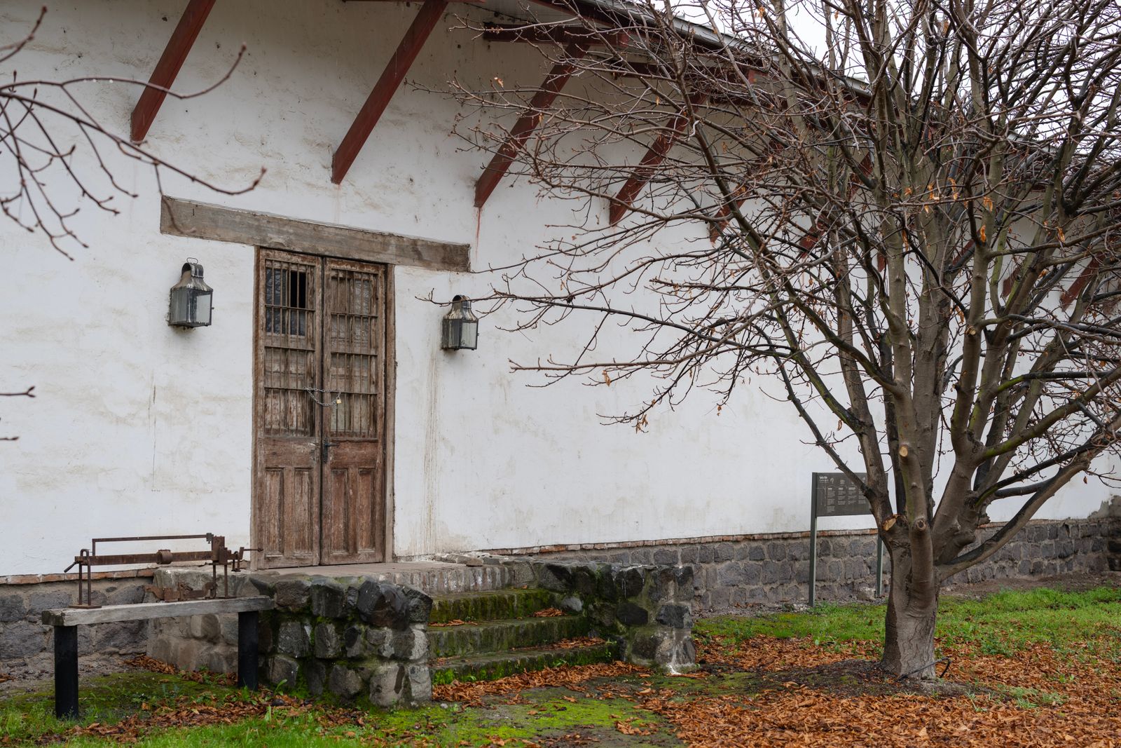 A whitewashed colonial facade in Santiago with a heavy wooden door and a bare tree. Photo by Miguel Cuenca on Pexels.