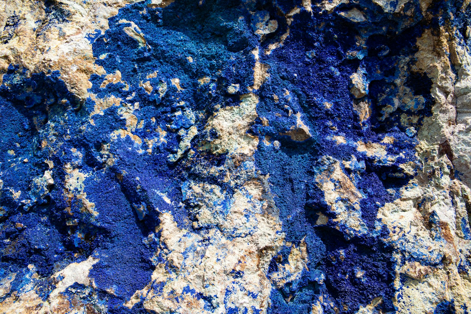 Deep blue mineral running through pale rock, seen close up. Photo by Geert Pieters on Unsplash.