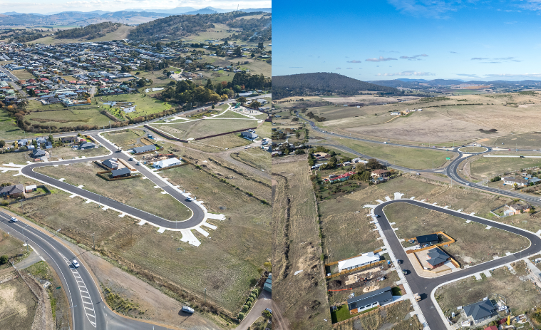 Aerial view of a suburban development with roads, houses, and open land under a blue sky.