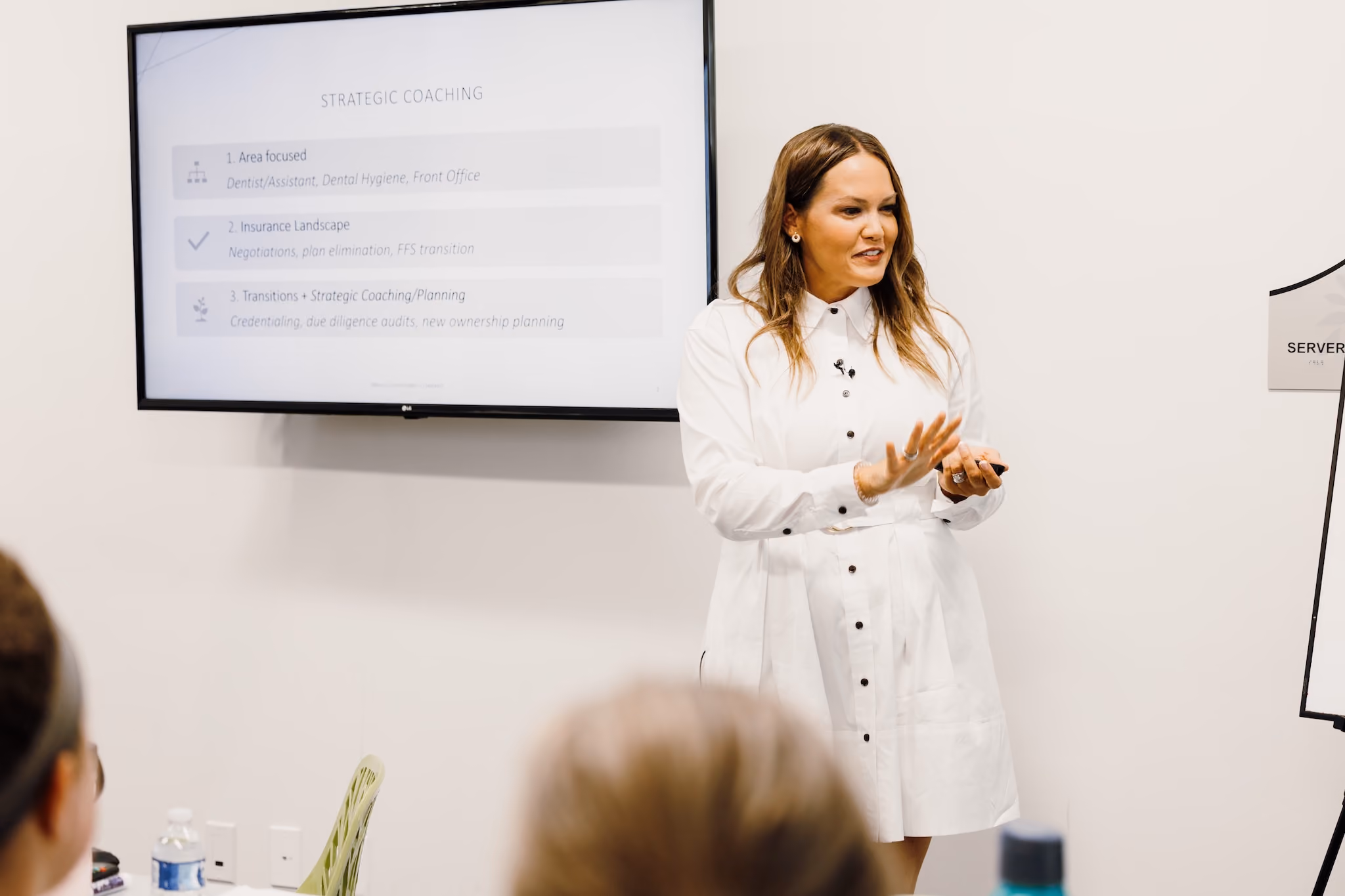 Woman giving a presentation on strategic coaching with bullet points on a wall screen.