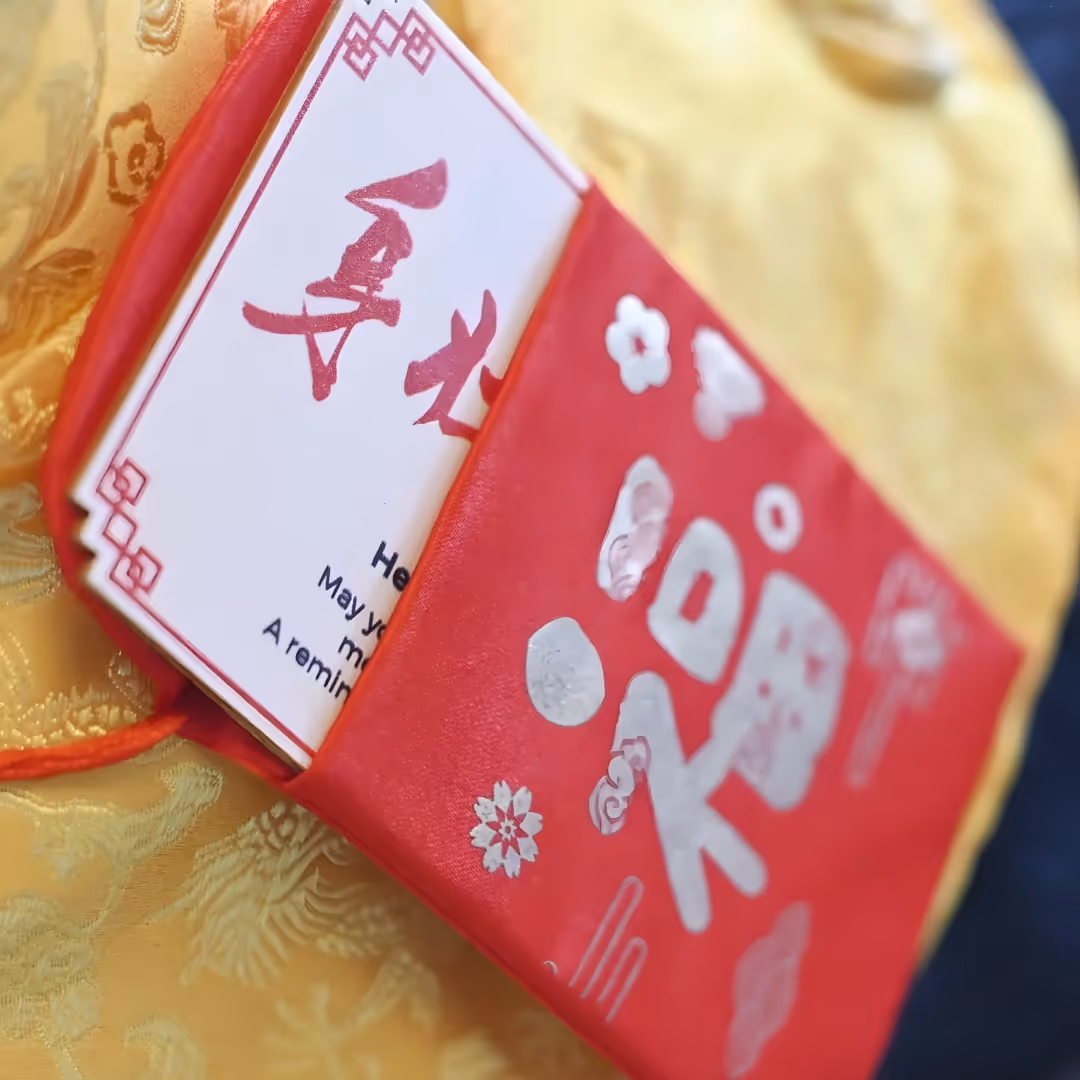 Red Chinese-style cloth book with silver characters placed on yellow embroidered fabric.