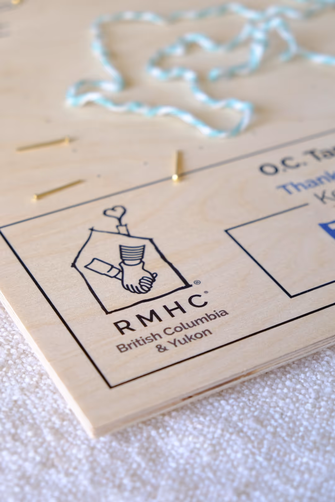 Wooden plaque with RMHC British Columbia & Yukon logo showing two hands holding inside a house outline.