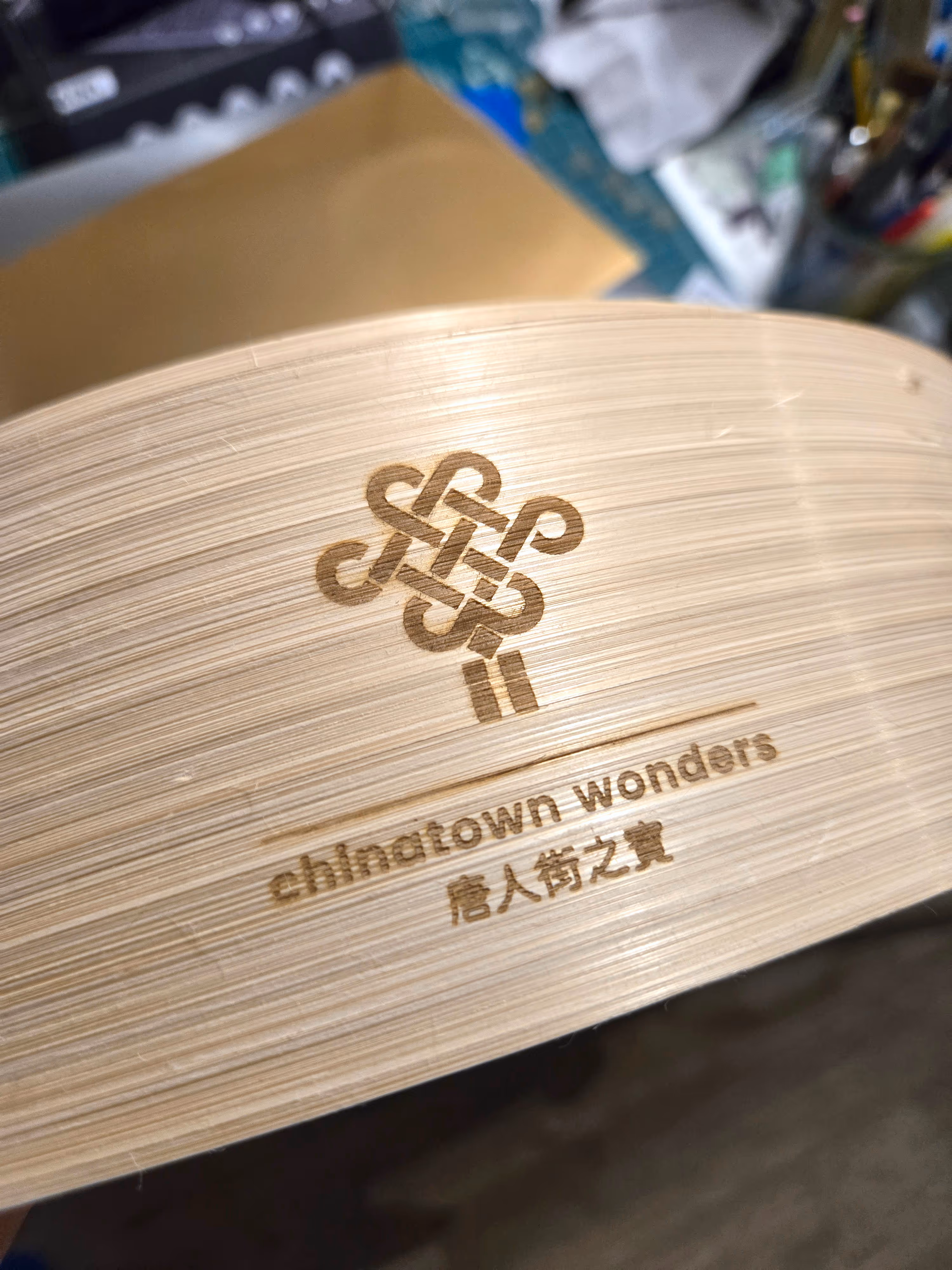 Close-up of wooden item engraved with a decorative knot and the text Chinatown wonders.